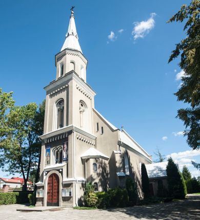 Zdjęcie nr 1: Kościół murowany, tynkowany, orientowany, jednonawowy. 
Prezbiterium prostokątne, zamknięte trójbocznie, od północy przylega zakrystia na planie prostokąta. Nawa szersza od prezbiterium, na rzucie prostokąta, od południa dostawiona kaplica Matki Boskiej na planie prostokąta, od zachodu wieża na planie kwadratu z dwoma aneksami po bokach. 
Prezbiterium dwuprzęsłowe, nawa trójprzęsłowa, nakryte sklepieniami krzyżowo-żebrowymi o gurtach spływających na profilowane wsporniki. Otwór tęczowy w formie półkolistej arkady. Parapet chóru muzycznego drewniany, wsparty na dwóch filarach.  Posadzka z płyt ceramicznych. 
Fasada wieżowa, jednoosiowa, trójkondygnacyjna, zwężająca się ku górze; dwie dolne kondygnacje na planie kwadratu, trzecia ośmioboku. Trzy ściany pierwszej kondygnacji wieży ujęte lizenami, zakończone profilowanym gzymsem z krenelażem oraz daszkiem pulpitowym. Na osi portal w formie stojącego prostokąta zamkniętego łukiem półkolistym, w opasce tynkowej z dwuskrzydłowymi drzwiami. Portal zamknięty od góry i po bokach uskokowym gzymsem z daszkiem pulpitowym. Nad portalem biforium. Trzy ściany drugiej kondygnacji wieży ujęte lizenami, zakończone profilowanym gzymsem z krenelażem oraz daszkiem pulpitowym. Na ścianach ślepe biforia we wnękach w formie stojącego prostokąta zamkniętego łukiem półkolistym. Trzecia kondygnacja zakończona profilowanym gzymsem z kostkowaniem, na ściankach otwory dzwonne w formie stojącego prostokąta zamkniętego łukiem półkolistym, naprzemiennie ślepe i otwarte. Wieża nakryta dachem ostrosłupowym. Po bokach wieży dwukondygnacyjne aneksy na planie wieloboku, przekryte daszkami wielospadowymi. 
Nawa i prezbiterium oszkarpowane w narożach jedno i dwuuskokowymi szkarpami nakrytymi daszkami. Na elewacji południowej pięć otworów okiennych w formie stojącego prostokąta zamkniętego łukiem półkolistym, z szerokim rozglifieniem. Na elewacji wschodniej dwa analogiczne okna, na północnej trzy. 
Nawa, kaplica i zakrystia nakryte dachami blaszanymi, dwuspadowymi, prezbiterium pięciospadowym. 