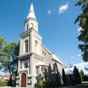 Zdjęcie nr 1: Kościół murowany, tynkowany, orientowany, jednonawowy. 
Prezbiterium prostokątne, zamknięte trójbocznie, od północy przylega zakrystia na planie prostokąta. Nawa szersza od prezbiterium, na rzucie prostokąta, od południa dostawiona kaplica Matki Boskiej na planie prostokąta, od zachodu wieża na planie kwadratu z dwoma aneksami po bokach. 
Prezbiterium dwuprzęsłowe, nawa trójprzęsłowa, nakryte sklepieniami krzyżowo-żebrowymi o gurtach spływających na profilowane wsporniki. Otwór tęczowy w formie półkolistej arkady. Parapet chóru muzycznego drewniany, wsparty na dwóch filarach.  Posadzka z płyt ceramicznych. 
Fasada wieżowa, jednoosiowa, trójkondygnacyjna, zwężająca się ku górze; dwie dolne kondygnacje na planie kwadratu, trzecia ośmioboku. Trzy ściany pierwszej kondygnacji wieży ujęte lizenami, zakończone profilowanym gzymsem z krenelażem oraz daszkiem pulpitowym. Na osi portal w formie stojącego prostokąta zamkniętego łukiem półkolistym, w opasce tynkowej z dwuskrzydłowymi drzwiami. Portal zamknięty od góry i po bokach uskokowym gzymsem z daszkiem pulpitowym. Nad portalem biforium. Trzy ściany drugiej kondygnacji wieży ujęte lizenami, zakończone profilowanym gzymsem z krenelażem oraz daszkiem pulpitowym. Na ścianach ślepe biforia we wnękach w formie stojącego prostokąta zamkniętego łukiem półkolistym. Trzecia kondygnacja zakończona profilowanym gzymsem z kostkowaniem, na ściankach otwory dzwonne w formie stojącego prostokąta zamkniętego łukiem półkolistym, naprzemiennie ślepe i otwarte. Wieża nakryta dachem ostrosłupowym. Po bokach wieży dwukondygnacyjne aneksy na planie wieloboku, przekryte daszkami wielospadowymi. 
Nawa i prezbiterium oszkarpowane w narożach jedno i dwuuskokowymi szkarpami nakrytymi daszkami. Na elewacji południowej pięć otworów okiennych w formie stojącego prostokąta zamkniętego łukiem półkolistym, z szerokim rozglifieniem. Na elewacji wschodniej dwa analogiczne okna, na północnej trzy. 
Nawa, kaplica i zakrystia nakryte dachami blaszanymi, dwuspadowymi, prezbiterium pięciospadowym. 