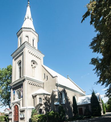 Zdjęcie nr 13: Kościół murowany, tynkowany, orientowany, jednonawowy. 
Prezbiterium prostokątne, zamknięte trójbocznie, od północy przylega zakrystia na planie prostokąta. Nawa szersza od prezbiterium, na rzucie prostokąta, od południa dostawiona kaplica Matki Boskiej na planie prostokąta, od zachodu wieża na planie kwadratu z dwoma aneksami po bokach. 
Prezbiterium dwuprzęsłowe, nawa trójprzęsłowa, nakryte sklepieniami krzyżowo-żebrowymi o gurtach spływających na profilowane wsporniki. Otwór tęczowy w formie półkolistej arkady. Parapet chóru muzycznego drewniany, wsparty na dwóch filarach.  Posadzka z płyt ceramicznych. 
Fasada wieżowa, jednoosiowa, trójkondygnacyjna, zwężająca się ku górze; dwie dolne kondygnacje na planie kwadratu, trzecia ośmioboku. Trzy ściany pierwszej kondygnacji wieży ujęte lizenami, zakończone profilowanym gzymsem z krenelażem oraz daszkiem pulpitowym. Na osi portal w formie stojącego prostokąta zamkniętego łukiem półkolistym, w opasce tynkowej z dwuskrzydłowymi drzwiami. Portal zamknięty od góry i po bokach uskokowym gzymsem z daszkiem pulpitowym. Nad portalem biforium. Trzy ściany drugiej kondygnacji wieży ujęte lizenami, zakończone profilowanym gzymsem z krenelażem oraz daszkiem pulpitowym. Na ścianach ślepe biforia we wnękach w formie stojącego prostokąta zamkniętego łukiem półkolistym. Trzecia kondygnacja zakończona profilowanym gzymsem z kostkowaniem, na ściankach otwory dzwonne w formie stojącego prostokąta zamkniętego łukiem półkolistym, naprzemiennie ślepe i otwarte. Wieża nakryta dachem ostrosłupowym. Po bokach wieży dwukondygnacyjne aneksy na planie wieloboku, przekryte daszkami wielospadowymi. 
Nawa i prezbiterium oszkarpowane w narożach jedno i dwuuskokowymi szkarpami nakrytymi daszkami. Na elewacji południowej pięć otworów okiennych w formie stojącego prostokąta zamkniętego łukiem półkolistym, z szerokim rozglifieniem. Na elewacji wschodniej dwa analogiczne okna, na północnej trzy. 
Nawa, kaplica i zakrystia nakryte dachami blaszanymi, dwuspadowymi, prezbiterium pięciospadowym. 