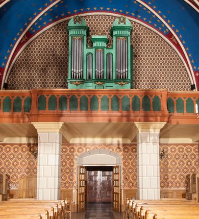 Zdjęcie nr 17: Kościół murowany, tynkowany, orientowany, jednonawowy. 
Prezbiterium prostokątne, zamknięte trójbocznie, od północy przylega zakrystia na planie prostokąta. Nawa szersza od prezbiterium, na rzucie prostokąta, od południa dostawiona kaplica Matki Boskiej na planie prostokąta, od zachodu wieża na planie kwadratu z dwoma aneksami po bokach. 
Prezbiterium dwuprzęsłowe, nawa trójprzęsłowa, nakryte sklepieniami krzyżowo-żebrowymi o gurtach spływających na profilowane wsporniki. Otwór tęczowy w formie półkolistej arkady. Parapet chóru muzycznego drewniany, wsparty na dwóch filarach.  Posadzka z płyt ceramicznych. 
Fasada wieżowa, jednoosiowa, trójkondygnacyjna, zwężająca się ku górze; dwie dolne kondygnacje na planie kwadratu, trzecia ośmioboku. Trzy ściany pierwszej kondygnacji wieży ujęte lizenami, zakończone profilowanym gzymsem z krenelażem oraz daszkiem pulpitowym. Na osi portal w formie stojącego prostokąta zamkniętego łukiem półkolistym, w opasce tynkowej z dwuskrzydłowymi drzwiami. Portal zamknięty od góry i po bokach uskokowym gzymsem z daszkiem pulpitowym. Nad portalem biforium. Trzy ściany drugiej kondygnacji wieży ujęte lizenami, zakończone profilowanym gzymsem z krenelażem oraz daszkiem pulpitowym. Na ścianach ślepe biforia we wnękach w formie stojącego prostokąta zamkniętego łukiem półkolistym. Trzecia kondygnacja zakończona profilowanym gzymsem z kostkowaniem, na ściankach otwory dzwonne w formie stojącego prostokąta zamkniętego łukiem półkolistym, naprzemiennie ślepe i otwarte. Wieża nakryta dachem ostrosłupowym. Po bokach wieży dwukondygnacyjne aneksy na planie wieloboku, przekryte daszkami wielospadowymi. 
Nawa i prezbiterium oszkarpowane w narożach jedno i dwuuskokowymi szkarpami nakrytymi daszkami. Na elewacji południowej pięć otworów okiennych w formie stojącego prostokąta zamkniętego łukiem półkolistym, z szerokim rozglifieniem. Na elewacji wschodniej dwa analogiczne okna, na północnej trzy. 
Nawa, kaplica i zakrystia nakryte dachami blaszanymi, dwuspadowymi, prezbiterium pięciospadowym. 