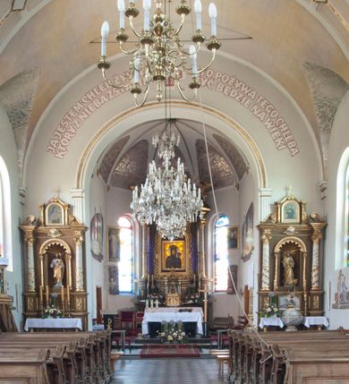 Zdjęcie nr 4: Kościół usytuowany w centrum wsi, u zbiegu głównych dróg, położony na niewielkim wzniesieniu, na placu otoczonym ogrodzeniem z kamiennymi filarami i metalową kratą. Budynek orientowany, jednonawowy, czteroprzęsłowy, z węższym prezbiterium zamkniętym trójbocznie. Od zachodu do fasady dostawiona niewielka kruchta; od południa dostawiona kaplica na planie prostokąta. Prezbiterium ujęte symetrycznie aneksami: pomieszczenie gospodarcze od północy i zakrystia od południa. Kościół sklepiony kolebkowo na gurtach z lunetami; prezbiterium nakryte sklepieniem parasolowatym; kaplica sklepieniem pseudoklasztornym; aneksy i kruchta z płaskim stropem. Wnętrze oświetlają prostokątne okna zamknięte półkoliście; w ścianie zachodniej okno okrągłe; w kaplicy i aneksach również okna zamknięte półkoliście. Wejście główne na osi kościoła, prostokątne; prezbiterium skomunikowane z aneksami prostokątnymi drzwiami; z zakrystii wyjście na zewnątrz. Chór muzyczny wsparty na czterech metalowych kolumnach z częścią środkową wybrzuszoną; z parapetem ozdobionym pseudopłycinami, kostkowaniem i  lambrekinem. Fasada jednoosiowa, jednokondygnacyjna z trójkątnym szczytem, ozdobiona krenelażem. Na osi kruchta, zamknięta trójkątnym szczytem z prostokątnym wejściem o półkolistym zwieńczeniu. Elewacje ujęte są uskokowymi przyporami i zwieńczone gzymsem z motywem lambrekinów. Dachy dwuspadowe nad nawą i prezbiterium; pulpitowe nad aneksami i kaplicą; kryte blachą. Dach wieńczy wieżyczka na sygnaturkę w formie gloriety zwieńczonej ostrosłupem z krzyżem.

Kaplica południowa na planie prostokąta, ze sklepieniem odwołującym się do formy sklepienia klasztornego. Szerokie wejście zakończone łukiem odcinkowym od strony nawy głównej. Naprzeciw wejścia okno zamknięte półkoliście, uskokowe wielokwaterowe. Wejście od strony zachodniej prostokątne, z drewnianymi drzwiami. Wnęka ołtarzowa zakończona łukiem półkolistym, z dekoracją mozaikową, przedstawiającą Michała Archanioła; podwieszona mensa ołtarzowa z lastriko. Część ołtarzowa podniesiona o jeden stopień.