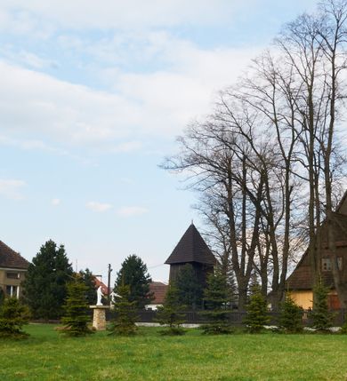 Zdjęcie nr 2: Kościół drewniany o konstrukcji zrębowej, na betonowym podmurowaniu przesłoniętym daszkiem gontowym, kruchta zachodnia o konstrukcji słupowo-ramowej. Elewacje jednolite, szalowane z listwowaniem, wzmocnione lisicami. Więźba dachowa drewniana, krokwiowa. Kościół orientowany, jednonawowy, nawa na rzucie prostokąta zbliżonego do kwadratu, prezbiterium nieco węższe, zakończone trójbocznie. Do wschodniej ściany prezbiterium przylega Ogrójec na rzucie prostokąta, od północy zakrystia na planie zbliżonym do trapezu. Do północnej ściany nawy przylega niewielka kruchta na rzucie prostokąta, od zachodu duża kruchta na planie prostokąta z pomieszczeniem nad nią, ze schodami drabiniastymi na chór, otwarta do nawy trzema dużymi otworami o wykroju prostokątnym. Wnętrze podzielone pilastrami podtrzymującymi architraw i fryz, wyłamane na ich osi. Pomiędzy nawą a prezbiterium prostokątny otwór tęczowy z prostą belką. Parapet chóru muzycznego w zachodniej części nawy, o wklęsło-wypukłym zarysie, podparty przez dwie kolumny i dwie półkolumny o wielobocznych trzonach. Otwory drzwiowe o prostokątnym wykroju zamknięte drzwiami spągowymi w północnej ścianie nawy oraz prezbiterium. Wnętrze nakryte pułapami deskowymi. Posadzka z płyt ceramicznych. 
Elewacja frontowa jednoosiowa, na osi wejście do kruchty z dwuskrzydłowymi drzwiami, w partii szczytu podwójne okno. W elewacji południowej cztery otwory okienne w formie stojącego prostokąta zamkniętego łukiem odcinkowym, dwa w nawie i dwa w prezbiterium oraz prostokątne, podwójne okno w kruchcie zachodniej, z krosnowymi oknami o drobnych podziałach kwaterowych. Elewacja północna z prostokątnym, podwójnym oknem w części kruchty zachodniej oraz z wejściami do kruchty północnej i do zakrystii o dwuskrzydłowych drzwiach. Na ścianie wschodniej prezbiterium Ogrójec w formie głębokiej szalowanej wnęki przesłoniętej daszkiem pulpitowym. Kościół nakryty dachami gontowymi dwuspadowymi, wyższym nad nawą, niższym nad prezbiterium, z kalenicą dekorowaną gontowym grzebieniem, nad zakrystią i kruchtą północną miękko modelowane dachy trójspadowe, kruchta zachodnia nakryta dachem dwuspadowym, półszczytowym. W połowie długości dachu nad nawą od strony prezbiterium wznosi się ponad kalenicą wieżyczka na sygnaturkę, na ośmiobocznym obitym blachą trzonie, z latarnią zwieńczoną niewielkim cebulastym hełmem.

 

