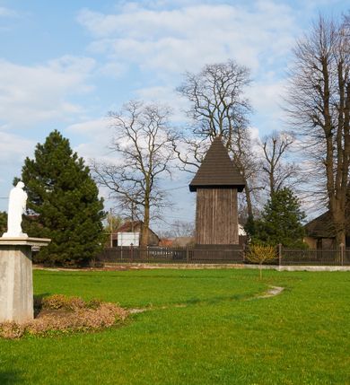 Zdjęcie nr 49: Kościół drewniany o konstrukcji zrębowej, na betonowym podmurowaniu przesłoniętym daszkiem gontowym, kruchta zachodnia o konstrukcji słupowo-ramowej. Elewacje jednolite, szalowane z listwowaniem, wzmocnione lisicami. Więźba dachowa drewniana, krokwiowa. Kościół orientowany, jednonawowy, nawa na rzucie prostokąta zbliżonego do kwadratu, prezbiterium nieco węższe, zakończone trójbocznie. Do wschodniej ściany prezbiterium przylega Ogrójec na rzucie prostokąta, od północy zakrystia na planie zbliżonym do trapezu. Do północnej ściany nawy przylega niewielka kruchta na rzucie prostokąta, od zachodu duża kruchta na planie prostokąta z pomieszczeniem nad nią, ze schodami drabiniastymi na chór, otwarta do nawy trzema dużymi otworami o wykroju prostokątnym. Wnętrze podzielone pilastrami podtrzymującymi architraw i fryz, wyłamane na ich osi. Pomiędzy nawą a prezbiterium prostokątny otwór tęczowy z prostą belką. Parapet chóru muzycznego w zachodniej części nawy, o wklęsło-wypukłym zarysie, podparty przez dwie kolumny i dwie półkolumny o wielobocznych trzonach. Otwory drzwiowe o prostokątnym wykroju zamknięte drzwiami spągowymi w północnej ścianie nawy oraz prezbiterium. Wnętrze nakryte pułapami deskowymi. Posadzka z płyt ceramicznych. 
Elewacja frontowa jednoosiowa, na osi wejście do kruchty z dwuskrzydłowymi drzwiami, w partii szczytu podwójne okno. W elewacji południowej cztery otwory okienne w formie stojącego prostokąta zamkniętego łukiem odcinkowym, dwa w nawie i dwa w prezbiterium oraz prostokątne, podwójne okno w kruchcie zachodniej, z krosnowymi oknami o drobnych podziałach kwaterowych. Elewacja północna z prostokątnym, podwójnym oknem w części kruchty zachodniej oraz z wejściami do kruchty północnej i do zakrystii o dwuskrzydłowych drzwiach. Na ścianie wschodniej prezbiterium Ogrójec w formie głębokiej szalowanej wnęki przesłoniętej daszkiem pulpitowym. Kościół nakryty dachami gontowymi dwuspadowymi, wyższym nad nawą, niższym nad prezbiterium, z kalenicą dekorowaną gontowym grzebieniem, nad zakrystią i kruchtą północną miękko modelowane dachy trójspadowe, kruchta zachodnia nakryta dachem dwuspadowym, półszczytowym. W połowie długości dachu nad nawą od strony prezbiterium wznosi się ponad kalenicą wieżyczka na sygnaturkę, na ośmiobocznym obitym blachą trzonie, z latarnią zwieńczoną niewielkim cebulastym hełmem.

 


