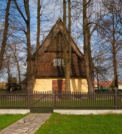 Zdjęcie nr 11: Kościół drewniany o konstrukcji zrębowej, na betonowym podmurowaniu przesłoniętym daszkiem gontowym, kruchta zachodnia o konstrukcji słupowo-ramowej. Elewacje jednolite, szalowane z listwowaniem, wzmocnione lisicami. Więźba dachowa drewniana, krokwiowa. Kościół orientowany, jednonawowy, nawa na rzucie prostokąta zbliżonego do kwadratu, prezbiterium nieco węższe, zakończone trójbocznie. Do wschodniej ściany prezbiterium przylega Ogrójec na rzucie prostokąta, od północy zakrystia na planie zbliżonym do trapezu. Do północnej ściany nawy przylega niewielka kruchta na rzucie prostokąta, od zachodu duża kruchta na planie prostokąta z pomieszczeniem nad nią, ze schodami drabiniastymi na chór, otwarta do nawy trzema dużymi otworami o wykroju prostokątnym. Wnętrze podzielone pilastrami podtrzymującymi architraw i fryz, wyłamane na ich osi. Pomiędzy nawą a prezbiterium prostokątny otwór tęczowy z prostą belką. Parapet chóru muzycznego w zachodniej części nawy, o wklęsło-wypukłym zarysie, podparty przez dwie kolumny i dwie półkolumny o wielobocznych trzonach. Otwory drzwiowe o prostokątnym wykroju zamknięte drzwiami spągowymi w północnej ścianie nawy oraz prezbiterium. Wnętrze nakryte pułapami deskowymi. Posadzka z płyt ceramicznych. 
Elewacja frontowa jednoosiowa, na osi wejście do kruchty z dwuskrzydłowymi drzwiami, w partii szczytu podwójne okno. W elewacji południowej cztery otwory okienne w formie stojącego prostokąta zamkniętego łukiem odcinkowym, dwa w nawie i dwa w prezbiterium oraz prostokątne, podwójne okno w kruchcie zachodniej, z krosnowymi oknami o drobnych podziałach kwaterowych. Elewacja północna z prostokątnym, podwójnym oknem w części kruchty zachodniej oraz z wejściami do kruchty północnej i do zakrystii o dwuskrzydłowych drzwiach. Na ścianie wschodniej prezbiterium Ogrójec w formie głębokiej szalowanej wnęki przesłoniętej daszkiem pulpitowym. Kościół nakryty dachami gontowymi dwuspadowymi, wyższym nad nawą, niższym nad prezbiterium, z kalenicą dekorowaną gontowym grzebieniem, nad zakrystią i kruchtą północną miękko modelowane dachy trójspadowe, kruchta zachodnia nakryta dachem dwuspadowym, półszczytowym. W połowie długości dachu nad nawą od strony prezbiterium wznosi się ponad kalenicą wieżyczka na sygnaturkę, na ośmiobocznym obitym blachą trzonie, z latarnią zwieńczoną niewielkim cebulastym hełmem.

 

