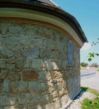 Zdjęcie nr 3: Kapliczkaa przydrożna, usytuowana przy szosie z Koźmic do Dobczyc, frontem zwrócona na północ, na planie prostokąta zbliżonego do kwadratu, zakończonego półkolista absydą. Przykryta dachem dwuspadowym, krytym blachą; z sygnaturką iglicową i z kulą zwieńczoną metalowym krzyżem. Fasada z prostym, trójkątnym szczytem i z prostokątnymi niszami zamkniętymi półkoliście. W środkowej, przeszklonej niszy umieszczona jest figura Matki Boskiej. Portal kamienny, zamknięty łukiem półkolistym z wyrytą na osi datą „1868 R.”. Drzwi jednoskrzydłowe, dubeltowe o zewnętrznej warstwie płycinowej z polichromowanym reliefem, przedstawiającym Oko Opatrzności. Pośrodku antaba żelazna; zawiasy kowalskie. Okna przeszklone, wielokwaterowe. Wnętrze jednoprzestrzenne z cementową posadzką (obecnie puste, kaplica jest w trakcie remontu). Na wyposażaniu ołtarz Matki Boskiej Różańcowej, figura św. Jana Nepomucena i drewniane, ludowe lichtarze.