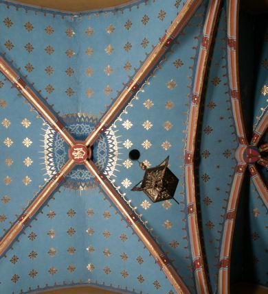 Zdjęcie nr 24: Kościół położony pośrodku wsi, na wysokiej skarpie, wzmocnionej murem. Otoczenie ogrodzone współcześnie. Od wschodu dzwonnica w formie bramy, ze schodami.  Kościół murowany, tynkowany, orientowany, zbudowany na planie wydłużonego prostokąta, jednonawowy, z węższym prezbiterium zamkniętym wielobocznie, opiętym szkarpami. Od północy przylega parterowa zakrystia z przedsionkiem, od południa dwie kruchty. Nawa od prezbiterium oddzielone ostrołukową arkadą. Wnętrze oświetlone oknami prostokątnymi zamkniętymi odcinkowo, wszystkie z witrażami. Nawa nakryta trójspadowym stropem, prezbiterium sklepieniem krzyżowo-żebrowym. Odrzwia z prezbiterium do zakrystii ostrołukowe. Okno w prezbiterium od wschodu ostrołukowe (zamurowane), okno w przedsionku zamknięte tzw. oślim grzbietem. Elewacje na kamiennym, obecnie tynkowanym cokole, oszkarpowane. Szkarpy uskokowe o zmiennym przekroju. Fasada jednoosiowa, zwieńczona trójkątnym szczytem. W osi elewacji ostrołukowy profilowany uskokowo portal, w szczycie okrągły otwór okienny, w płaskiej, tynkowanej opasce. Szczyt dodatkowo podzielony lizenami, u góry zdobiony fryzem arkadkowym, zamknięty wydatnym, profilowanym gzymsem. Oś elewacji zaakcentowana pośrodku wykonanym w tynku i zróżnicowanym kolorystycznie krzyżem, umieszczonym nad wejściem. Po lewej stronie portalu marmurowa tablica epitafijna. Po prawej stronie portalu marmurowa prostokątna tablica z donatorami. Elewacja zachodnia zamknięta wielobocznie, oszkarpowana. W górnej części ostrołukowa blenda, poniżej umieszczony krucyfiks, osłonięty dwuspadowym daszkiem, wspartym na konsolkach. Elewacje boczne pięcioosiowe z prostokątnymi otworami drzwiowymi w drugich osiach od zachodu. Poszczególne osie oddzielone prostokątnymi oknami. Zakrystia i kruchty nakryte dachem jednospadowym. Konstrukcja dachu korpusu głównego drewniana, krokwiowo-płatwiowa. Dach dwuspadowy, nad prezbiterium trójspadowy, kryty blachą ocynkowaną. Sygnaturka w całości obita blachą. Dzwonnica posiada dwie kondygnacje: dolną przeprutą dwiema arkadami, tworzącymi wejście w obręb cmentarza kościelnego i górną, przedzieloną czterema arkadami, przeznaczonymi na pomieszczenie dzwonów. Dach siodłowy.
