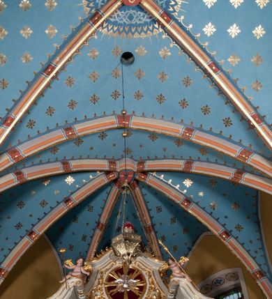 Zdjęcie nr 18: Kościół położony pośrodku wsi, na wysokiej skarpie, wzmocnionej murem. Otoczenie ogrodzone współcześnie. Od wschodu dzwonnica w formie bramy, ze schodami.  Kościół murowany, tynkowany, orientowany, zbudowany na planie wydłużonego prostokąta, jednonawowy, z węższym prezbiterium zamkniętym wielobocznie, opiętym szkarpami. Od północy przylega parterowa zakrystia z przedsionkiem, od południa dwie kruchty. Nawa od prezbiterium oddzielone ostrołukową arkadą. Wnętrze oświetlone oknami prostokątnymi zamkniętymi odcinkowo, wszystkie z witrażami. Nawa nakryta trójspadowym stropem, prezbiterium sklepieniem krzyżowo-żebrowym. Odrzwia z prezbiterium do zakrystii ostrołukowe. Okno w prezbiterium od wschodu ostrołukowe (zamurowane), okno w przedsionku zamknięte tzw. oślim grzbietem. Elewacje na kamiennym, obecnie tynkowanym cokole, oszkarpowane. Szkarpy uskokowe o zmiennym przekroju. Fasada jednoosiowa, zwieńczona trójkątnym szczytem. W osi elewacji ostrołukowy profilowany uskokowo portal, w szczycie okrągły otwór okienny, w płaskiej, tynkowanej opasce. Szczyt dodatkowo podzielony lizenami, u góry zdobiony fryzem arkadkowym, zamknięty wydatnym, profilowanym gzymsem. Oś elewacji zaakcentowana pośrodku wykonanym w tynku i zróżnicowanym kolorystycznie krzyżem, umieszczonym nad wejściem. Po lewej stronie portalu marmurowa tablica epitafijna. Po prawej stronie portalu marmurowa prostokątna tablica z donatorami. Elewacja zachodnia zamknięta wielobocznie, oszkarpowana. W górnej części ostrołukowa blenda, poniżej umieszczony krucyfiks, osłonięty dwuspadowym daszkiem, wspartym na konsolkach. Elewacje boczne pięcioosiowe z prostokątnymi otworami drzwiowymi w drugich osiach od zachodu. Poszczególne osie oddzielone prostokątnymi oknami. Zakrystia i kruchty nakryte dachem jednospadowym. Konstrukcja dachu korpusu głównego drewniana, krokwiowo-płatwiowa. Dach dwuspadowy, nad prezbiterium trójspadowy, kryty blachą ocynkowaną. Sygnaturka w całości obita blachą. Dzwonnica posiada dwie kondygnacje: dolną przeprutą dwiema arkadami, tworzącymi wejście w obręb cmentarza kościelnego i górną, przedzieloną czterema arkadami, przeznaczonymi na pomieszczenie dzwonów. Dach siodłowy.
