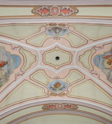 Zdjęcie nr 23: Kościół położony pośrodku wsi, na wysokiej skarpie, wzmocnionej murem. Otoczenie ogrodzone współcześnie. Od wschodu dzwonnica w formie bramy, ze schodami.  Kościół murowany, tynkowany, orientowany, zbudowany na planie wydłużonego prostokąta, jednonawowy, z węższym prezbiterium zamkniętym wielobocznie, opiętym szkarpami. Od północy przylega parterowa zakrystia z przedsionkiem, od południa dwie kruchty. Nawa od prezbiterium oddzielone ostrołukową arkadą. Wnętrze oświetlone oknami prostokątnymi zamkniętymi odcinkowo, wszystkie z witrażami. Nawa nakryta trójspadowym stropem, prezbiterium sklepieniem krzyżowo-żebrowym. Odrzwia z prezbiterium do zakrystii ostrołukowe. Okno w prezbiterium od wschodu ostrołukowe (zamurowane), okno w przedsionku zamknięte tzw. oślim grzbietem. Elewacje na kamiennym, obecnie tynkowanym cokole, oszkarpowane. Szkarpy uskokowe o zmiennym przekroju. Fasada jednoosiowa, zwieńczona trójkątnym szczytem. W osi elewacji ostrołukowy profilowany uskokowo portal, w szczycie okrągły otwór okienny, w płaskiej, tynkowanej opasce. Szczyt dodatkowo podzielony lizenami, u góry zdobiony fryzem arkadkowym, zamknięty wydatnym, profilowanym gzymsem. Oś elewacji zaakcentowana pośrodku wykonanym w tynku i zróżnicowanym kolorystycznie krzyżem, umieszczonym nad wejściem. Po lewej stronie portalu marmurowa tablica epitafijna. Po prawej stronie portalu marmurowa prostokątna tablica z donatorami. Elewacja zachodnia zamknięta wielobocznie, oszkarpowana. W górnej części ostrołukowa blenda, poniżej umieszczony krucyfiks, osłonięty dwuspadowym daszkiem, wspartym na konsolkach. Elewacje boczne pięcioosiowe z prostokątnymi otworami drzwiowymi w drugich osiach od zachodu. Poszczególne osie oddzielone prostokątnymi oknami. Zakrystia i kruchty nakryte dachem jednospadowym. Konstrukcja dachu korpusu głównego drewniana, krokwiowo-płatwiowa. Dach dwuspadowy, nad prezbiterium trójspadowy, kryty blachą ocynkowaną. Sygnaturka w całości obita blachą. Dzwonnica posiada dwie kondygnacje: dolną przeprutą dwiema arkadami, tworzącymi wejście w obręb cmentarza kościelnego i górną, przedzieloną czterema arkadami, przeznaczonymi na pomieszczenie dzwonów. Dach siodłowy.
