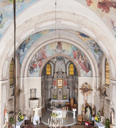 Zdjęcie nr 9: Kościół pw. Opieki Matki Boskiej w Kamieniu usytuowany jest na niewielkiej, wydzielonej ogrodzeniem działce usytuowanej na południe od głównej drogi wiodącej przez miejscowość. Kamieński kościół to budowla murowana z kamienia i cegły, orientowana, jednonawowa z nawą na rzucie prostokąta opiętą dziesięcioma trójuskokowymi przyporami oraz nieco węższym i półokrągło zamkniętym prezbiterium. Od strony północnej do prezbiterium przylega zakrystia na planie prostokąta. Do północno-zachodniej części nawy dostawiona jest niewielka, prostokątna kruchta. Wnętrze świątyni sklepiono sklepieniem kolebkowym z lunetami. Nawę i prezbiterium nakrywają dachy dwuspadowe, natomiast wieżę dach ostrosłupowy o czterech połaciach zwieńczony niewielkim krzyżem. Pierwotnie świątynia przekryta była dachem z czerwonej dachówki, którą w 1985 roku wymieniono na obecne pokrycie z ocynkowanej blachy. Więźbę dachową o konstrukcji płatwiowo-kleszczowej z krzyżującymi się stolcami wykonano z drewna sosnowego. Do wnętrza świątyni prowadzą trzy wejścia – główne z kruchtą od strony zachodniej, boczne również z kruchtą, z której wychodzi się na chór muzyczny i wieżę od strony północnej oraz wejście przez zakrystię. Do wejścia głównego prowadziły masywne, betonowe schody na rzucie półokręgu wylane w 1928 roku, które w 1981 roku zostały zastąpione obecnymi schodami na rzucie prostokąta. W trójosiowej i trójkondygnacyjnej fasadzie świątyni zaakcentowana wysunięciem do przodu jest oś środkowa przechodząca w górnej części w czworoboczną wieżę. W jej pierwszej kondygnacji mieści się zadaszony, opracowany w cegle, neobarokowy portal główny. Wieńczy go gzyms o kształcie łuku kotarowego, na szczycie którego znajduje się krzyż. W portalu umieszczone są dwuskrzydłowe, drewniane drzwi zamknięte łukiem półokrągłym. Ponad otworem wejściowym, w osi portalu znajduje się przeszklona rozeta. W kondygnacjach drugiej i trzeciej omawianej osi środkowej fasady mieszczą się półkoliście zamknięte okna. W osiach skrajnych nieregularnie rozmieszczono niewielkie, prostokątne okna, w kondygnacji pierwszej zamknięte półkoliście. Elewacje boczne świątyni są czteroosiowe i jednokondygnacyjne, z wyjątkiem trzykondygnacyjnej osi pierwszej, w której od strony północnej mieści się prostokątna kruchta, ponad którą rozmieszczono dwa półokrągło zamknięte okna, po jednym w kondygnacji drugiej i trzeciej. Od strony południowej we wszystkich kondygnacjach mieszczą się półokrągłe okna. Elewacje boczne nawy artykułowane są przyporami, pomiędzy którymi znajdują się okna zamknięte łukiem półokrągłym. W prezbiterium od strony wschodniej mieszczą się dwa półokrągłe okna.