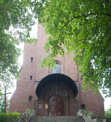 Zdjęcie nr 24: Kościół pw. Opieki Matki Boskiej w Kamieniu usytuowany jest na niewielkiej, wydzielonej ogrodzeniem działce usytuowanej na południe od głównej drogi wiodącej przez miejscowość. Kamieński kościół to budowla murowana z kamienia i cegły, orientowana, jednonawowa z nawą na rzucie prostokąta opiętą dziesięcioma trójuskokowymi przyporami oraz nieco węższym i półokrągło zamkniętym prezbiterium. Od strony północnej do prezbiterium przylega zakrystia na planie prostokąta. Do północno-zachodniej części nawy dostawiona jest niewielka, prostokątna kruchta. Wnętrze świątyni sklepiono sklepieniem kolebkowym z lunetami. Nawę i prezbiterium nakrywają dachy dwuspadowe, natomiast wieżę dach ostrosłupowy o czterech połaciach zwieńczony niewielkim krzyżem. Pierwotnie świątynia przekryta była dachem z czerwonej dachówki, którą w 1985 roku wymieniono na obecne pokrycie z ocynkowanej blachy. Więźbę dachową o konstrukcji płatwiowo-kleszczowej z krzyżującymi się stolcami wykonano z drewna sosnowego. Do wnętrza świątyni prowadzą trzy wejścia – główne z kruchtą od strony zachodniej, boczne również z kruchtą, z której wychodzi się na chór muzyczny i wieżę od strony północnej oraz wejście przez zakrystię. Do wejścia głównego prowadziły masywne, betonowe schody na rzucie półokręgu wylane w 1928 roku, które w 1981 roku zostały zastąpione obecnymi schodami na rzucie prostokąta. W trójosiowej i trójkondygnacyjnej fasadzie świątyni zaakcentowana wysunięciem do przodu jest oś środkowa przechodząca w górnej części w czworoboczną wieżę. W jej pierwszej kondygnacji mieści się zadaszony, opracowany w cegle, neobarokowy portal główny. Wieńczy go gzyms o kształcie łuku kotarowego, na szczycie którego znajduje się krzyż. W portalu umieszczone są dwuskrzydłowe, drewniane drzwi zamknięte łukiem półokrągłym. Ponad otworem wejściowym, w osi portalu znajduje się przeszklona rozeta. W kondygnacjach drugiej i trzeciej omawianej osi środkowej fasady mieszczą się półkoliście zamknięte okna. W osiach skrajnych nieregularnie rozmieszczono niewielkie, prostokątne okna, w kondygnacji pierwszej zamknięte półkoliście. Elewacje boczne świątyni są czteroosiowe i jednokondygnacyjne, z wyjątkiem trzykondygnacyjnej osi pierwszej, w której od strony północnej mieści się prostokątna kruchta, ponad którą rozmieszczono dwa półokrągło zamknięte okna, po jednym w kondygnacji drugiej i trzeciej. Od strony południowej we wszystkich kondygnacjach mieszczą się półokrągłe okna. Elewacje boczne nawy artykułowane są przyporami, pomiędzy którymi znajdują się okna zamknięte łukiem półokrągłym. W prezbiterium od strony wschodniej mieszczą się dwa półokrągłe okna.