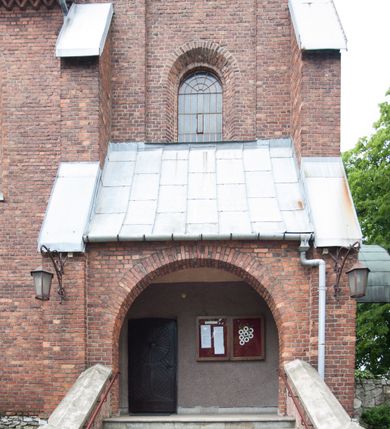 Zdjęcie nr 4: Kościół pw. Opieki Matki Boskiej w Kamieniu usytuowany jest na niewielkiej, wydzielonej ogrodzeniem działce usytuowanej na południe od głównej drogi wiodącej przez miejscowość. Kamieński kościół to budowla murowana z kamienia i cegły, orientowana, jednonawowa z nawą na rzucie prostokąta opiętą dziesięcioma trójuskokowymi przyporami oraz nieco węższym i półokrągło zamkniętym prezbiterium. Od strony północnej do prezbiterium przylega zakrystia na planie prostokąta. Do północno-zachodniej części nawy dostawiona jest niewielka, prostokątna kruchta. Wnętrze świątyni sklepiono sklepieniem kolebkowym z lunetami. Nawę i prezbiterium nakrywają dachy dwuspadowe, natomiast wieżę dach ostrosłupowy o czterech połaciach zwieńczony niewielkim krzyżem. Pierwotnie świątynia przekryta była dachem z czerwonej dachówki, którą w 1985 roku wymieniono na obecne pokrycie z ocynkowanej blachy. Więźbę dachową o konstrukcji płatwiowo-kleszczowej z krzyżującymi się stolcami wykonano z drewna sosnowego. Do wnętrza świątyni prowadzą trzy wejścia – główne z kruchtą od strony zachodniej, boczne również z kruchtą, z której wychodzi się na chór muzyczny i wieżę od strony północnej oraz wejście przez zakrystię. Do wejścia głównego prowadziły masywne, betonowe schody na rzucie półokręgu wylane w 1928 roku, które w 1981 roku zostały zastąpione obecnymi schodami na rzucie prostokąta. W trójosiowej i trójkondygnacyjnej fasadzie świątyni zaakcentowana wysunięciem do przodu jest oś środkowa przechodząca w górnej części w czworoboczną wieżę. W jej pierwszej kondygnacji mieści się zadaszony, opracowany w cegle, neobarokowy portal główny. Wieńczy go gzyms o kształcie łuku kotarowego, na szczycie którego znajduje się krzyż. W portalu umieszczone są dwuskrzydłowe, drewniane drzwi zamknięte łukiem półokrągłym. Ponad otworem wejściowym, w osi portalu znajduje się przeszklona rozeta. W kondygnacjach drugiej i trzeciej omawianej osi środkowej fasady mieszczą się półkoliście zamknięte okna. W osiach skrajnych nieregularnie rozmieszczono niewielkie, prostokątne okna, w kondygnacji pierwszej zamknięte półkoliście. Elewacje boczne świątyni są czteroosiowe i jednokondygnacyjne, z wyjątkiem trzykondygnacyjnej osi pierwszej, w której od strony północnej mieści się prostokątna kruchta, ponad którą rozmieszczono dwa półokrągło zamknięte okna, po jednym w kondygnacji drugiej i trzeciej. Od strony południowej we wszystkich kondygnacjach mieszczą się półokrągłe okna. Elewacje boczne nawy artykułowane są przyporami, pomiędzy którymi znajdują się okna zamknięte łukiem półokrągłym. W prezbiterium od strony wschodniej mieszczą się dwa półokrągłe okna.