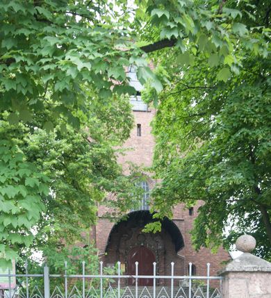 Zdjęcie nr 32: Kościół pw. Opieki Matki Boskiej w Kamieniu usytuowany jest na niewielkiej, wydzielonej ogrodzeniem działce usytuowanej na południe od głównej drogi wiodącej przez miejscowość. Kamieński kościół to budowla murowana z kamienia i cegły, orientowana, jednonawowa z nawą na rzucie prostokąta opiętą dziesięcioma trójuskokowymi przyporami oraz nieco węższym i półokrągło zamkniętym prezbiterium. Od strony północnej do prezbiterium przylega zakrystia na planie prostokąta. Do północno-zachodniej części nawy dostawiona jest niewielka, prostokątna kruchta. Wnętrze świątyni sklepiono sklepieniem kolebkowym z lunetami. Nawę i prezbiterium nakrywają dachy dwuspadowe, natomiast wieżę dach ostrosłupowy o czterech połaciach zwieńczony niewielkim krzyżem. Pierwotnie świątynia przekryta była dachem z czerwonej dachówki, którą w 1985 roku wymieniono na obecne pokrycie z ocynkowanej blachy. Więźbę dachową o konstrukcji płatwiowo-kleszczowej z krzyżującymi się stolcami wykonano z drewna sosnowego. Do wnętrza świątyni prowadzą trzy wejścia – główne z kruchtą od strony zachodniej, boczne również z kruchtą, z której wychodzi się na chór muzyczny i wieżę od strony północnej oraz wejście przez zakrystię. Do wejścia głównego prowadziły masywne, betonowe schody na rzucie półokręgu wylane w 1928 roku, które w 1981 roku zostały zastąpione obecnymi schodami na rzucie prostokąta. W trójosiowej i trójkondygnacyjnej fasadzie świątyni zaakcentowana wysunięciem do przodu jest oś środkowa przechodząca w górnej części w czworoboczną wieżę. W jej pierwszej kondygnacji mieści się zadaszony, opracowany w cegle, neobarokowy portal główny. Wieńczy go gzyms o kształcie łuku kotarowego, na szczycie którego znajduje się krzyż. W portalu umieszczone są dwuskrzydłowe, drewniane drzwi zamknięte łukiem półokrągłym. Ponad otworem wejściowym, w osi portalu znajduje się przeszklona rozeta. W kondygnacjach drugiej i trzeciej omawianej osi środkowej fasady mieszczą się półkoliście zamknięte okna. W osiach skrajnych nieregularnie rozmieszczono niewielkie, prostokątne okna, w kondygnacji pierwszej zamknięte półkoliście. Elewacje boczne świątyni są czteroosiowe i jednokondygnacyjne, z wyjątkiem trzykondygnacyjnej osi pierwszej, w której od strony północnej mieści się prostokątna kruchta, ponad którą rozmieszczono dwa półokrągło zamknięte okna, po jednym w kondygnacji drugiej i trzeciej. Od strony południowej we wszystkich kondygnacjach mieszczą się półokrągłe okna. Elewacje boczne nawy artykułowane są przyporami, pomiędzy którymi znajdują się okna zamknięte łukiem półokrągłym. W prezbiterium od strony wschodniej mieszczą się dwa półokrągłe okna.