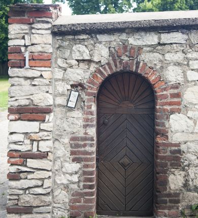 Zdjęcie nr 3: Kościół pw. Opieki Matki Boskiej w Kamieniu usytuowany jest na niewielkiej, wydzielonej ogrodzeniem działce usytuowanej na południe od głównej drogi wiodącej przez miejscowość. Kamieński kościół to budowla murowana z kamienia i cegły, orientowana, jednonawowa z nawą na rzucie prostokąta opiętą dziesięcioma trójuskokowymi przyporami oraz nieco węższym i półokrągło zamkniętym prezbiterium. Od strony północnej do prezbiterium przylega zakrystia na planie prostokąta. Do północno-zachodniej części nawy dostawiona jest niewielka, prostokątna kruchta. Wnętrze świątyni sklepiono sklepieniem kolebkowym z lunetami. Nawę i prezbiterium nakrywają dachy dwuspadowe, natomiast wieżę dach ostrosłupowy o czterech połaciach zwieńczony niewielkim krzyżem. Pierwotnie świątynia przekryta była dachem z czerwonej dachówki, którą w 1985 roku wymieniono na obecne pokrycie z ocynkowanej blachy. Więźbę dachową o konstrukcji płatwiowo-kleszczowej z krzyżującymi się stolcami wykonano z drewna sosnowego. Do wnętrza świątyni prowadzą trzy wejścia – główne z kruchtą od strony zachodniej, boczne również z kruchtą, z której wychodzi się na chór muzyczny i wieżę od strony północnej oraz wejście przez zakrystię. Do wejścia głównego prowadziły masywne, betonowe schody na rzucie półokręgu wylane w 1928 roku, które w 1981 roku zostały zastąpione obecnymi schodami na rzucie prostokąta. W trójosiowej i trójkondygnacyjnej fasadzie świątyni zaakcentowana wysunięciem do przodu jest oś środkowa przechodząca w górnej części w czworoboczną wieżę. W jej pierwszej kondygnacji mieści się zadaszony, opracowany w cegle, neobarokowy portal główny. Wieńczy go gzyms o kształcie łuku kotarowego, na szczycie którego znajduje się krzyż. W portalu umieszczone są dwuskrzydłowe, drewniane drzwi zamknięte łukiem półokrągłym. Ponad otworem wejściowym, w osi portalu znajduje się przeszklona rozeta. W kondygnacjach drugiej i trzeciej omawianej osi środkowej fasady mieszczą się półkoliście zamknięte okna. W osiach skrajnych nieregularnie rozmieszczono niewielkie, prostokątne okna, w kondygnacji pierwszej zamknięte półkoliście. Elewacje boczne świątyni są czteroosiowe i jednokondygnacyjne, z wyjątkiem trzykondygnacyjnej osi pierwszej, w której od strony północnej mieści się prostokątna kruchta, ponad którą rozmieszczono dwa półokrągło zamknięte okna, po jednym w kondygnacji drugiej i trzeciej. Od strony południowej we wszystkich kondygnacjach mieszczą się półokrągłe okna. Elewacje boczne nawy artykułowane są przyporami, pomiędzy którymi znajdują się okna zamknięte łukiem półokrągłym. W prezbiterium od strony wschodniej mieszczą się dwa półokrągłe okna.