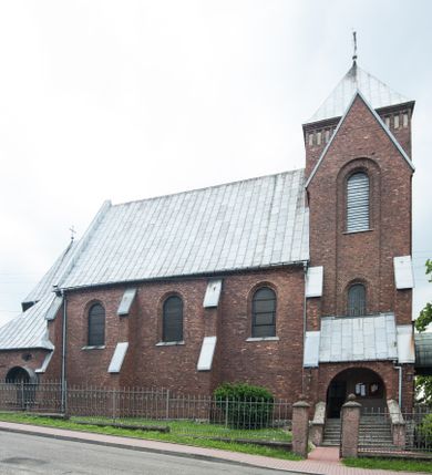 Zdjęcie nr 1: Kościół pw. Opieki Matki Boskiej w Kamieniu usytuowany jest na niewielkiej, wydzielonej ogrodzeniem działce usytuowanej na południe od głównej drogi wiodącej przez miejscowość. Kamieński kościół to budowla murowana z kamienia i cegły, orientowana, jednonawowa z nawą na rzucie prostokąta opiętą dziesięcioma trójuskokowymi przyporami oraz nieco węższym i półokrągło zamkniętym prezbiterium. Od strony północnej do prezbiterium przylega zakrystia na planie prostokąta. Do północno-zachodniej części nawy dostawiona jest niewielka, prostokątna kruchta. Wnętrze świątyni sklepiono sklepieniem kolebkowym z lunetami. Nawę i prezbiterium nakrywają dachy dwuspadowe, natomiast wieżę dach ostrosłupowy o czterech połaciach zwieńczony niewielkim krzyżem. Pierwotnie świątynia przekryta była dachem z czerwonej dachówki, którą w 1985 roku wymieniono na obecne pokrycie z ocynkowanej blachy. Więźbę dachową o konstrukcji płatwiowo-kleszczowej z krzyżującymi się stolcami wykonano z drewna sosnowego. Do wnętrza świątyni prowadzą trzy wejścia – główne z kruchtą od strony zachodniej, boczne również z kruchtą, z której wychodzi się na chór muzyczny i wieżę od strony północnej oraz wejście przez zakrystię. Do wejścia głównego prowadziły masywne, betonowe schody na rzucie półokręgu wylane w 1928 roku, które w 1981 roku zostały zastąpione obecnymi schodami na rzucie prostokąta. W trójosiowej i trójkondygnacyjnej fasadzie świątyni zaakcentowana wysunięciem do przodu jest oś środkowa przechodząca w górnej części w czworoboczną wieżę. W jej pierwszej kondygnacji mieści się zadaszony, opracowany w cegle, neobarokowy portal główny. Wieńczy go gzyms o kształcie łuku kotarowego, na szczycie którego znajduje się krzyż. W portalu umieszczone są dwuskrzydłowe, drewniane drzwi zamknięte łukiem półokrągłym. Ponad otworem wejściowym, w osi portalu znajduje się przeszklona rozeta. W kondygnacjach drugiej i trzeciej omawianej osi środkowej fasady mieszczą się półkoliście zamknięte okna. W osiach skrajnych nieregularnie rozmieszczono niewielkie, prostokątne okna, w kondygnacji pierwszej zamknięte półkoliście. Elewacje boczne świątyni są czteroosiowe i jednokondygnacyjne, z wyjątkiem trzykondygnacyjnej osi pierwszej, w której od strony północnej mieści się prostokątna kruchta, ponad którą rozmieszczono dwa półokrągło zamknięte okna, po jednym w kondygnacji drugiej i trzeciej. Od strony południowej we wszystkich kondygnacjach mieszczą się półokrągłe okna. Elewacje boczne nawy artykułowane są przyporami, pomiędzy którymi znajdują się okna zamknięte łukiem półokrągłym. W prezbiterium od strony wschodniej mieszczą się dwa półokrągłe okna.