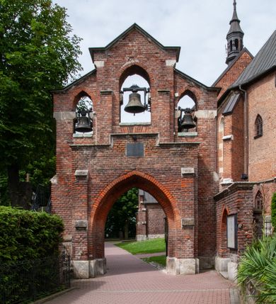 Zdjęcie nr 6: Kościół jest zlokalizowany na wzgórzu, w centrum wsi. Murowany z cegły, w wątku polskim, z zendrówką. Kościół jest orientowany, założony na planie prostokąta, jednonawowy, trójprzęsłowy, z dobudowanymi kruchtami od zachodu i południa. Prezbiterium oddzielone od nawy łukiem tęczowym, dwuprzęsłowe na planie prostokąta, zamknięte prostą ścianą, z dwukondygnacyjną przybudówką zakończoną trójbocznie. Nawa została przykryta sklepieniem sieciowym. Ściana południowa nawy przepruta trzema prostokątnymi oknami, zamkniętymi łukiem ostrym. Okna w nawie i prezbiterium dwudzielne, z sześcioma mniejszymi kwaterami. Przybudówka przy prezbiterium na parterze mieści zakrystię, a na piętrze składzik. Kruchta południowa sklepiona kolebką. Z kruchty do nawy prowadzi ostrołukowy, kamienny portal o dwóch archiwoltach. Kruchta zachodnia, obecnie kaplica św. Franciszka, sklepiona spłaszczoną, ukrytą kopułą na pendentywach. Ściana zachodnia kruchty przepruta dwoma ostrołukowymi oknami i ponad nimi okrągłym oknem. Od południa ostrołukowe wejście. Kościół o zróżnicowanej wysokości nawy i prezbiterium. Ściany opięte szkarpami. Na jednej trzeciej wysokości ścian oraz w zwieńczeniu nawy i prezbiterium profilowany gzyms. Od zachodu wklęsło-wypukły szczyt. Nawa, prezbiterium i dwie kruchty przykryte dachem dwuspadowym. Nad drugim przęsłem prezbiterium wieżyczka na sygnaturkę na planie ośmioboku, z profilowanym gzymsem i latarnią, zwieńczoną hełmem z kulą i krzyżem. Wejście do kościoła od południa i zachodu. Okna nawy i prezbiterium z kamiennym obramieniem. Nad wejściem do kruchty południowej formowany w cegle ostry łuk. Analogiczny łuk nad oknami w ścianie zachodniej i nad blendą w ścianie północnej. W przybudówce do prezbiterium dwie kondygnacje okien zamkniętych łukiem ostrym. W ścianie frontowej prostokątne wejście, a nad nim półkoliście zamknięta wnęka z grupą Ukrzyżowania. 


