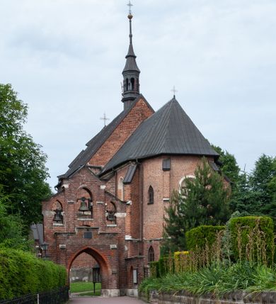 Zdjęcie nr 1: Kościół jest zlokalizowany na wzgórzu, w centrum wsi. Murowany z cegły, w wątku polskim, z zendrówką. Kościół jest orientowany, założony na planie prostokąta, jednonawowy, trójprzęsłowy, z dobudowanymi kruchtami od zachodu i południa. Prezbiterium oddzielone od nawy łukiem tęczowym, dwuprzęsłowe na planie prostokąta, zamknięte prostą ścianą, z dwukondygnacyjną przybudówką zakończoną trójbocznie. Nawa została przykryta sklepieniem sieciowym. Ściana południowa nawy przepruta trzema prostokątnymi oknami, zamkniętymi łukiem ostrym. Okna w nawie i prezbiterium dwudzielne, z sześcioma mniejszymi kwaterami. Przybudówka przy prezbiterium na parterze mieści zakrystię, a na piętrze składzik. Kruchta południowa sklepiona kolebką. Z kruchty do nawy prowadzi ostrołukowy, kamienny portal o dwóch archiwoltach. Kruchta zachodnia, obecnie kaplica św. Franciszka, sklepiona spłaszczoną, ukrytą kopułą na pendentywach. Ściana zachodnia kruchty przepruta dwoma ostrołukowymi oknami i ponad nimi okrągłym oknem. Od południa ostrołukowe wejście. Kościół o zróżnicowanej wysokości nawy i prezbiterium. Ściany opięte szkarpami. Na jednej trzeciej wysokości ścian oraz w zwieńczeniu nawy i prezbiterium profilowany gzyms. Od zachodu wklęsło-wypukły szczyt. Nawa, prezbiterium i dwie kruchty przykryte dachem dwuspadowym. Nad drugim przęsłem prezbiterium wieżyczka na sygnaturkę na planie ośmioboku, z profilowanym gzymsem i latarnią, zwieńczoną hełmem z kulą i krzyżem. Wejście do kościoła od południa i zachodu. Okna nawy i prezbiterium z kamiennym obramieniem. Nad wejściem do kruchty południowej formowany w cegle ostry łuk. Analogiczny łuk nad oknami w ścianie zachodniej i nad blendą w ścianie północnej. W przybudówce do prezbiterium dwie kondygnacje okien zamkniętych łukiem ostrym. W ścianie frontowej prostokątne wejście, a nad nim półkoliście zamknięta wnęka z grupą Ukrzyżowania. 


