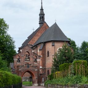 Zdjęcie nr 1: Kościół jest zlokalizowany na wzgórzu, w centrum wsi. Murowany z cegły, w wątku polskim, z zendrówką. Kościół jest orientowany, założony na planie prostokąta, jednonawowy, trójprzęsłowy, z dobudowanymi kruchtami od zachodu i południa. Prezbiterium oddzielone od nawy łukiem tęczowym, dwuprzęsłowe na planie prostokąta, zamknięte prostą ścianą, z dwukondygnacyjną przybudówką zakończoną trójbocznie. Nawa została przykryta sklepieniem sieciowym. Ściana południowa nawy przepruta trzema prostokątnymi oknami, zamkniętymi łukiem ostrym. Okna w nawie i prezbiterium dwudzielne, z sześcioma mniejszymi kwaterami. Przybudówka przy prezbiterium na parterze mieści zakrystię, a na piętrze składzik. Kruchta południowa sklepiona kolebką. Z kruchty do nawy prowadzi ostrołukowy, kamienny portal o dwóch archiwoltach. Kruchta zachodnia, obecnie kaplica św. Franciszka, sklepiona spłaszczoną, ukrytą kopułą na pendentywach. Ściana zachodnia kruchty przepruta dwoma ostrołukowymi oknami i ponad nimi okrągłym oknem. Od południa ostrołukowe wejście. Kościół o zróżnicowanej wysokości nawy i prezbiterium. Ściany opięte szkarpami. Na jednej trzeciej wysokości ścian oraz w zwieńczeniu nawy i prezbiterium profilowany gzyms. Od zachodu wklęsło-wypukły szczyt. Nawa, prezbiterium i dwie kruchty przykryte dachem dwuspadowym. Nad drugim przęsłem prezbiterium wieżyczka na sygnaturkę na planie ośmioboku, z profilowanym gzymsem i latarnią, zwieńczoną hełmem z kulą i krzyżem. Wejście do kościoła od południa i zachodu. Okna nawy i prezbiterium z kamiennym obramieniem. Nad wejściem do kruchty południowej formowany w cegle ostry łuk. Analogiczny łuk nad oknami w ścianie zachodniej i nad blendą w ścianie północnej. W przybudówce do prezbiterium dwie kondygnacje okien zamkniętych łukiem ostrym. W ścianie frontowej prostokątne wejście, a nad nim półkoliście zamknięta wnęka z grupą Ukrzyżowania. 


