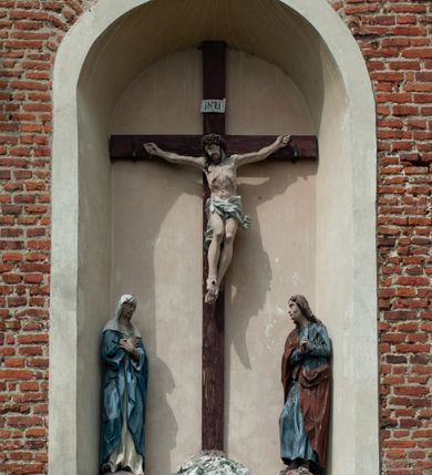 Zdjęcie nr 32: Kościół jest zlokalizowany na wzgórzu, w centrum wsi. Murowany z cegły, w wątku polskim, z zendrówką. Kościół jest orientowany, założony na planie prostokąta, jednonawowy, trójprzęsłowy, z dobudowanymi kruchtami od zachodu i południa. Prezbiterium oddzielone od nawy łukiem tęczowym, dwuprzęsłowe na planie prostokąta, zamknięte prostą ścianą, z dwukondygnacyjną przybudówką zakończoną trójbocznie. Nawa została przykryta sklepieniem sieciowym. Ściana południowa nawy przepruta trzema prostokątnymi oknami, zamkniętymi łukiem ostrym. Okna w nawie i prezbiterium dwudzielne, z sześcioma mniejszymi kwaterami. Przybudówka przy prezbiterium na parterze mieści zakrystię, a na piętrze składzik. Kruchta południowa sklepiona kolebką. Z kruchty do nawy prowadzi ostrołukowy, kamienny portal o dwóch archiwoltach. Kruchta zachodnia, obecnie kaplica św. Franciszka, sklepiona spłaszczoną, ukrytą kopułą na pendentywach. Ściana zachodnia kruchty przepruta dwoma ostrołukowymi oknami i ponad nimi okrągłym oknem. Od południa ostrołukowe wejście. Kościół o zróżnicowanej wysokości nawy i prezbiterium. Ściany opięte szkarpami. Na jednej trzeciej wysokości ścian oraz w zwieńczeniu nawy i prezbiterium profilowany gzyms. Od zachodu wklęsło-wypukły szczyt. Nawa, prezbiterium i dwie kruchty przykryte dachem dwuspadowym. Nad drugim przęsłem prezbiterium wieżyczka na sygnaturkę na planie ośmioboku, z profilowanym gzymsem i latarnią, zwieńczoną hełmem z kulą i krzyżem. Wejście do kościoła od południa i zachodu. Okna nawy i prezbiterium z kamiennym obramieniem. Nad wejściem do kruchty południowej formowany w cegle ostry łuk. Analogiczny łuk nad oknami w ścianie zachodniej i nad blendą w ścianie północnej. W przybudówce do prezbiterium dwie kondygnacje okien zamkniętych łukiem ostrym. W ścianie frontowej prostokątne wejście, a nad nim półkoliście zamknięta wnęka z grupą Ukrzyżowania. 


