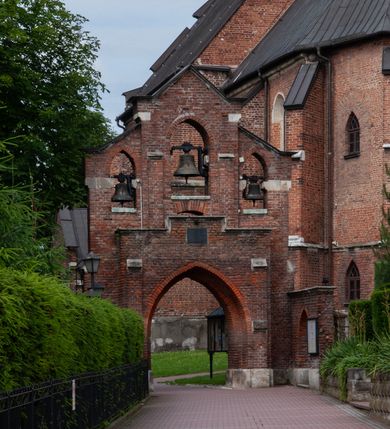 Zdjęcie nr 5: Kościół jest zlokalizowany na wzgórzu, w centrum wsi. Murowany z cegły, w wątku polskim, z zendrówką. Kościół jest orientowany, założony na planie prostokąta, jednonawowy, trójprzęsłowy, z dobudowanymi kruchtami od zachodu i południa. Prezbiterium oddzielone od nawy łukiem tęczowym, dwuprzęsłowe na planie prostokąta, zamknięte prostą ścianą, z dwukondygnacyjną przybudówką zakończoną trójbocznie. Nawa została przykryta sklepieniem sieciowym. Ściana południowa nawy przepruta trzema prostokątnymi oknami, zamkniętymi łukiem ostrym. Okna w nawie i prezbiterium dwudzielne, z sześcioma mniejszymi kwaterami. Przybudówka przy prezbiterium na parterze mieści zakrystię, a na piętrze składzik. Kruchta południowa sklepiona kolebką. Z kruchty do nawy prowadzi ostrołukowy, kamienny portal o dwóch archiwoltach. Kruchta zachodnia, obecnie kaplica św. Franciszka, sklepiona spłaszczoną, ukrytą kopułą na pendentywach. Ściana zachodnia kruchty przepruta dwoma ostrołukowymi oknami i ponad nimi okrągłym oknem. Od południa ostrołukowe wejście. Kościół o zróżnicowanej wysokości nawy i prezbiterium. Ściany opięte szkarpami. Na jednej trzeciej wysokości ścian oraz w zwieńczeniu nawy i prezbiterium profilowany gzyms. Od zachodu wklęsło-wypukły szczyt. Nawa, prezbiterium i dwie kruchty przykryte dachem dwuspadowym. Nad drugim przęsłem prezbiterium wieżyczka na sygnaturkę na planie ośmioboku, z profilowanym gzymsem i latarnią, zwieńczoną hełmem z kulą i krzyżem. Wejście do kościoła od południa i zachodu. Okna nawy i prezbiterium z kamiennym obramieniem. Nad wejściem do kruchty południowej formowany w cegle ostry łuk. Analogiczny łuk nad oknami w ścianie zachodniej i nad blendą w ścianie północnej. W przybudówce do prezbiterium dwie kondygnacje okien zamkniętych łukiem ostrym. W ścianie frontowej prostokątne wejście, a nad nim półkoliście zamknięta wnęka z grupą Ukrzyżowania. 


