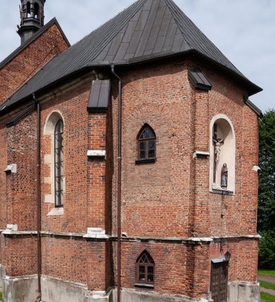 Zdjęcie nr 24: Kościół jest zlokalizowany na wzgórzu, w centrum wsi. Murowany z cegły, w wątku polskim, z zendrówką. Kościół jest orientowany, założony na planie prostokąta, jednonawowy, trójprzęsłowy, z dobudowanymi kruchtami od zachodu i południa. Prezbiterium oddzielone od nawy łukiem tęczowym, dwuprzęsłowe na planie prostokąta, zamknięte prostą ścianą, z dwukondygnacyjną przybudówką zakończoną trójbocznie. Nawa została przykryta sklepieniem sieciowym. Ściana południowa nawy przepruta trzema prostokątnymi oknami, zamkniętymi łukiem ostrym. Okna w nawie i prezbiterium dwudzielne, z sześcioma mniejszymi kwaterami. Przybudówka przy prezbiterium na parterze mieści zakrystię, a na piętrze składzik. Kruchta południowa sklepiona kolebką. Z kruchty do nawy prowadzi ostrołukowy, kamienny portal o dwóch archiwoltach. Kruchta zachodnia, obecnie kaplica św. Franciszka, sklepiona spłaszczoną, ukrytą kopułą na pendentywach. Ściana zachodnia kruchty przepruta dwoma ostrołukowymi oknami i ponad nimi okrągłym oknem. Od południa ostrołukowe wejście. Kościół o zróżnicowanej wysokości nawy i prezbiterium. Ściany opięte szkarpami. Na jednej trzeciej wysokości ścian oraz w zwieńczeniu nawy i prezbiterium profilowany gzyms. Od zachodu wklęsło-wypukły szczyt. Nawa, prezbiterium i dwie kruchty przykryte dachem dwuspadowym. Nad drugim przęsłem prezbiterium wieżyczka na sygnaturkę na planie ośmioboku, z profilowanym gzymsem i latarnią, zwieńczoną hełmem z kulą i krzyżem. Wejście do kościoła od południa i zachodu. Okna nawy i prezbiterium z kamiennym obramieniem. Nad wejściem do kruchty południowej formowany w cegle ostry łuk. Analogiczny łuk nad oknami w ścianie zachodniej i nad blendą w ścianie północnej. W przybudówce do prezbiterium dwie kondygnacje okien zamkniętych łukiem ostrym. W ścianie frontowej prostokątne wejście, a nad nim półkoliście zamknięta wnęka z grupą Ukrzyżowania. 


