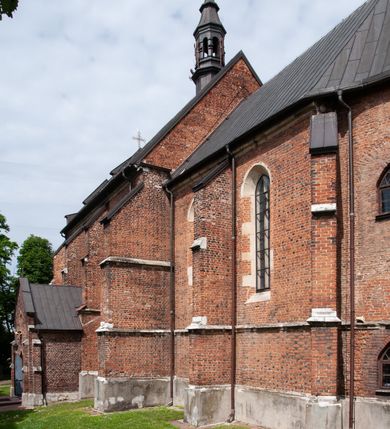 Zdjęcie nr 29: Kościół jest zlokalizowany na wzgórzu, w centrum wsi. Murowany z cegły, w wątku polskim, z zendrówką. Kościół jest orientowany, założony na planie prostokąta, jednonawowy, trójprzęsłowy, z dobudowanymi kruchtami od zachodu i południa. Prezbiterium oddzielone od nawy łukiem tęczowym, dwuprzęsłowe na planie prostokąta, zamknięte prostą ścianą, z dwukondygnacyjną przybudówką zakończoną trójbocznie. Nawa została przykryta sklepieniem sieciowym. Ściana południowa nawy przepruta trzema prostokątnymi oknami, zamkniętymi łukiem ostrym. Okna w nawie i prezbiterium dwudzielne, z sześcioma mniejszymi kwaterami. Przybudówka przy prezbiterium na parterze mieści zakrystię, a na piętrze składzik. Kruchta południowa sklepiona kolebką. Z kruchty do nawy prowadzi ostrołukowy, kamienny portal o dwóch archiwoltach. Kruchta zachodnia, obecnie kaplica św. Franciszka, sklepiona spłaszczoną, ukrytą kopułą na pendentywach. Ściana zachodnia kruchty przepruta dwoma ostrołukowymi oknami i ponad nimi okrągłym oknem. Od południa ostrołukowe wejście. Kościół o zróżnicowanej wysokości nawy i prezbiterium. Ściany opięte szkarpami. Na jednej trzeciej wysokości ścian oraz w zwieńczeniu nawy i prezbiterium profilowany gzyms. Od zachodu wklęsło-wypukły szczyt. Nawa, prezbiterium i dwie kruchty przykryte dachem dwuspadowym. Nad drugim przęsłem prezbiterium wieżyczka na sygnaturkę na planie ośmioboku, z profilowanym gzymsem i latarnią, zwieńczoną hełmem z kulą i krzyżem. Wejście do kościoła od południa i zachodu. Okna nawy i prezbiterium z kamiennym obramieniem. Nad wejściem do kruchty południowej formowany w cegle ostry łuk. Analogiczny łuk nad oknami w ścianie zachodniej i nad blendą w ścianie północnej. W przybudówce do prezbiterium dwie kondygnacje okien zamkniętych łukiem ostrym. W ścianie frontowej prostokątne wejście, a nad nim półkoliście zamknięta wnęka z grupą Ukrzyżowania. 


