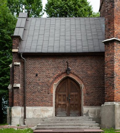 Zdjęcie nr 49: Kościół jest zlokalizowany na wzgórzu, w centrum wsi. Murowany z cegły, w wątku polskim, z zendrówką. Kościół jest orientowany, założony na planie prostokąta, jednonawowy, trójprzęsłowy, z dobudowanymi kruchtami od zachodu i południa. Prezbiterium oddzielone od nawy łukiem tęczowym, dwuprzęsłowe na planie prostokąta, zamknięte prostą ścianą, z dwukondygnacyjną przybudówką zakończoną trójbocznie. Nawa została przykryta sklepieniem sieciowym. Ściana południowa nawy przepruta trzema prostokątnymi oknami, zamkniętymi łukiem ostrym. Okna w nawie i prezbiterium dwudzielne, z sześcioma mniejszymi kwaterami. Przybudówka przy prezbiterium na parterze mieści zakrystię, a na piętrze składzik. Kruchta południowa sklepiona kolebką. Z kruchty do nawy prowadzi ostrołukowy, kamienny portal o dwóch archiwoltach. Kruchta zachodnia, obecnie kaplica św. Franciszka, sklepiona spłaszczoną, ukrytą kopułą na pendentywach. Ściana zachodnia kruchty przepruta dwoma ostrołukowymi oknami i ponad nimi okrągłym oknem. Od południa ostrołukowe wejście. Kościół o zróżnicowanej wysokości nawy i prezbiterium. Ściany opięte szkarpami. Na jednej trzeciej wysokości ścian oraz w zwieńczeniu nawy i prezbiterium profilowany gzyms. Od zachodu wklęsło-wypukły szczyt. Nawa, prezbiterium i dwie kruchty przykryte dachem dwuspadowym. Nad drugim przęsłem prezbiterium wieżyczka na sygnaturkę na planie ośmioboku, z profilowanym gzymsem i latarnią, zwieńczoną hełmem z kulą i krzyżem. Wejście do kościoła od południa i zachodu. Okna nawy i prezbiterium z kamiennym obramieniem. Nad wejściem do kruchty południowej formowany w cegle ostry łuk. Analogiczny łuk nad oknami w ścianie zachodniej i nad blendą w ścianie północnej. W przybudówce do prezbiterium dwie kondygnacje okien zamkniętych łukiem ostrym. W ścianie frontowej prostokątne wejście, a nad nim półkoliście zamknięta wnęka z grupą Ukrzyżowania. 


