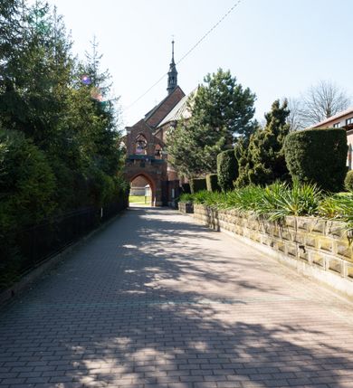 Zdjęcie nr 2: Kościół jest zlokalizowany na wzgórzu, w centrum wsi. Murowany z cegły, w wątku polskim, z zendrówką. Kościół jest orientowany, założony na planie prostokąta, jednonawowy, trójprzęsłowy, z dobudowanymi kruchtami od zachodu i południa. Prezbiterium oddzielone od nawy łukiem tęczowym, dwuprzęsłowe na planie prostokąta, zamknięte prostą ścianą, z dwukondygnacyjną przybudówką zakończoną trójbocznie. Nawa została przykryta sklepieniem sieciowym. Ściana południowa nawy przepruta trzema prostokątnymi oknami, zamkniętymi łukiem ostrym. Okna w nawie i prezbiterium dwudzielne, z sześcioma mniejszymi kwaterami. Przybudówka przy prezbiterium na parterze mieści zakrystię, a na piętrze składzik. Kruchta południowa sklepiona kolebką. Z kruchty do nawy prowadzi ostrołukowy, kamienny portal o dwóch archiwoltach. Kruchta zachodnia, obecnie kaplica św. Franciszka, sklepiona spłaszczoną, ukrytą kopułą na pendentywach. Ściana zachodnia kruchty przepruta dwoma ostrołukowymi oknami i ponad nimi okrągłym oknem. Od południa ostrołukowe wejście. Kościół o zróżnicowanej wysokości nawy i prezbiterium. Ściany opięte szkarpami. Na jednej trzeciej wysokości ścian oraz w zwieńczeniu nawy i prezbiterium profilowany gzyms. Od zachodu wklęsło-wypukły szczyt. Nawa, prezbiterium i dwie kruchty przykryte dachem dwuspadowym. Nad drugim przęsłem prezbiterium wieżyczka na sygnaturkę na planie ośmioboku, z profilowanym gzymsem i latarnią, zwieńczoną hełmem z kulą i krzyżem. Wejście do kościoła od południa i zachodu. Okna nawy i prezbiterium z kamiennym obramieniem. Nad wejściem do kruchty południowej formowany w cegle ostry łuk. Analogiczny łuk nad oknami w ścianie zachodniej i nad blendą w ścianie północnej. W przybudówce do prezbiterium dwie kondygnacje okien zamkniętych łukiem ostrym. W ścianie frontowej prostokątne wejście, a nad nim półkoliście zamknięta wnęka z grupą Ukrzyżowania. 


