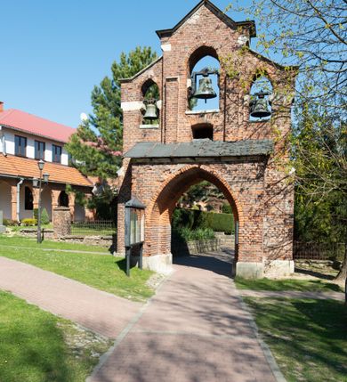 Zdjęcie nr 15: Kościół jest zlokalizowany na wzgórzu, w centrum wsi. Murowany z cegły, w wątku polskim, z zendrówką. Kościół jest orientowany, założony na planie prostokąta, jednonawowy, trójprzęsłowy, z dobudowanymi kruchtami od zachodu i południa. Prezbiterium oddzielone od nawy łukiem tęczowym, dwuprzęsłowe na planie prostokąta, zamknięte prostą ścianą, z dwukondygnacyjną przybudówką zakończoną trójbocznie. Nawa została przykryta sklepieniem sieciowym. Ściana południowa nawy przepruta trzema prostokątnymi oknami, zamkniętymi łukiem ostrym. Okna w nawie i prezbiterium dwudzielne, z sześcioma mniejszymi kwaterami. Przybudówka przy prezbiterium na parterze mieści zakrystię, a na piętrze składzik. Kruchta południowa sklepiona kolebką. Z kruchty do nawy prowadzi ostrołukowy, kamienny portal o dwóch archiwoltach. Kruchta zachodnia, obecnie kaplica św. Franciszka, sklepiona spłaszczoną, ukrytą kopułą na pendentywach. Ściana zachodnia kruchty przepruta dwoma ostrołukowymi oknami i ponad nimi okrągłym oknem. Od południa ostrołukowe wejście. Kościół o zróżnicowanej wysokości nawy i prezbiterium. Ściany opięte szkarpami. Na jednej trzeciej wysokości ścian oraz w zwieńczeniu nawy i prezbiterium profilowany gzyms. Od zachodu wklęsło-wypukły szczyt. Nawa, prezbiterium i dwie kruchty przykryte dachem dwuspadowym. Nad drugim przęsłem prezbiterium wieżyczka na sygnaturkę na planie ośmioboku, z profilowanym gzymsem i latarnią, zwieńczoną hełmem z kulą i krzyżem. Wejście do kościoła od południa i zachodu. Okna nawy i prezbiterium z kamiennym obramieniem. Nad wejściem do kruchty południowej formowany w cegle ostry łuk. Analogiczny łuk nad oknami w ścianie zachodniej i nad blendą w ścianie północnej. W przybudówce do prezbiterium dwie kondygnacje okien zamkniętych łukiem ostrym. W ścianie frontowej prostokątne wejście, a nad nim półkoliście zamknięta wnęka z grupą Ukrzyżowania. 


