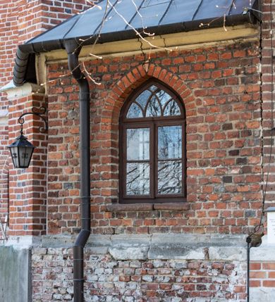 Zdjęcie nr 69: Kościół jest zlokalizowany na wzgórzu, w centrum wsi. Murowany z cegły, w wątku polskim, z zendrówką. Kościół jest orientowany, założony na planie prostokąta, jednonawowy, trójprzęsłowy, z dobudowanymi kruchtami od zachodu i południa. Prezbiterium oddzielone od nawy łukiem tęczowym, dwuprzęsłowe na planie prostokąta, zamknięte prostą ścianą, z dwukondygnacyjną przybudówką zakończoną trójbocznie. Nawa została przykryta sklepieniem sieciowym. Ściana południowa nawy przepruta trzema prostokątnymi oknami, zamkniętymi łukiem ostrym. Okna w nawie i prezbiterium dwudzielne, z sześcioma mniejszymi kwaterami. Przybudówka przy prezbiterium na parterze mieści zakrystię, a na piętrze składzik. Kruchta południowa sklepiona kolebką. Z kruchty do nawy prowadzi ostrołukowy, kamienny portal o dwóch archiwoltach. Kruchta zachodnia, obecnie kaplica św. Franciszka, sklepiona spłaszczoną, ukrytą kopułą na pendentywach. Ściana zachodnia kruchty przepruta dwoma ostrołukowymi oknami i ponad nimi okrągłym oknem. Od południa ostrołukowe wejście. Kościół o zróżnicowanej wysokości nawy i prezbiterium. Ściany opięte szkarpami. Na jednej trzeciej wysokości ścian oraz w zwieńczeniu nawy i prezbiterium profilowany gzyms. Od zachodu wklęsło-wypukły szczyt. Nawa, prezbiterium i dwie kruchty przykryte dachem dwuspadowym. Nad drugim przęsłem prezbiterium wieżyczka na sygnaturkę na planie ośmioboku, z profilowanym gzymsem i latarnią, zwieńczoną hełmem z kulą i krzyżem. Wejście do kościoła od południa i zachodu. Okna nawy i prezbiterium z kamiennym obramieniem. Nad wejściem do kruchty południowej formowany w cegle ostry łuk. Analogiczny łuk nad oknami w ścianie zachodniej i nad blendą w ścianie północnej. W przybudówce do prezbiterium dwie kondygnacje okien zamkniętych łukiem ostrym. W ścianie frontowej prostokątne wejście, a nad nim półkoliście zamknięta wnęka z grupą Ukrzyżowania. 


