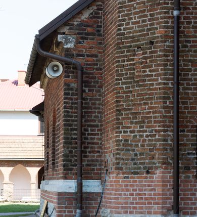 Zdjęcie nr 58: Kościół jest zlokalizowany na wzgórzu, w centrum wsi. Murowany z cegły, w wątku polskim, z zendrówką. Kościół jest orientowany, założony na planie prostokąta, jednonawowy, trójprzęsłowy, z dobudowanymi kruchtami od zachodu i południa. Prezbiterium oddzielone od nawy łukiem tęczowym, dwuprzęsłowe na planie prostokąta, zamknięte prostą ścianą, z dwukondygnacyjną przybudówką zakończoną trójbocznie. Nawa została przykryta sklepieniem sieciowym. Ściana południowa nawy przepruta trzema prostokątnymi oknami, zamkniętymi łukiem ostrym. Okna w nawie i prezbiterium dwudzielne, z sześcioma mniejszymi kwaterami. Przybudówka przy prezbiterium na parterze mieści zakrystię, a na piętrze składzik. Kruchta południowa sklepiona kolebką. Z kruchty do nawy prowadzi ostrołukowy, kamienny portal o dwóch archiwoltach. Kruchta zachodnia, obecnie kaplica św. Franciszka, sklepiona spłaszczoną, ukrytą kopułą na pendentywach. Ściana zachodnia kruchty przepruta dwoma ostrołukowymi oknami i ponad nimi okrągłym oknem. Od południa ostrołukowe wejście. Kościół o zróżnicowanej wysokości nawy i prezbiterium. Ściany opięte szkarpami. Na jednej trzeciej wysokości ścian oraz w zwieńczeniu nawy i prezbiterium profilowany gzyms. Od zachodu wklęsło-wypukły szczyt. Nawa, prezbiterium i dwie kruchty przykryte dachem dwuspadowym. Nad drugim przęsłem prezbiterium wieżyczka na sygnaturkę na planie ośmioboku, z profilowanym gzymsem i latarnią, zwieńczoną hełmem z kulą i krzyżem. Wejście do kościoła od południa i zachodu. Okna nawy i prezbiterium z kamiennym obramieniem. Nad wejściem do kruchty południowej formowany w cegle ostry łuk. Analogiczny łuk nad oknami w ścianie zachodniej i nad blendą w ścianie północnej. W przybudówce do prezbiterium dwie kondygnacje okien zamkniętych łukiem ostrym. W ścianie frontowej prostokątne wejście, a nad nim półkoliście zamknięta wnęka z grupą Ukrzyżowania. 


