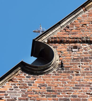 Zdjęcie nr 63: Kościół jest zlokalizowany na wzgórzu, w centrum wsi. Murowany z cegły, w wątku polskim, z zendrówką. Kościół jest orientowany, założony na planie prostokąta, jednonawowy, trójprzęsłowy, z dobudowanymi kruchtami od zachodu i południa. Prezbiterium oddzielone od nawy łukiem tęczowym, dwuprzęsłowe na planie prostokąta, zamknięte prostą ścianą, z dwukondygnacyjną przybudówką zakończoną trójbocznie. Nawa została przykryta sklepieniem sieciowym. Ściana południowa nawy przepruta trzema prostokątnymi oknami, zamkniętymi łukiem ostrym. Okna w nawie i prezbiterium dwudzielne, z sześcioma mniejszymi kwaterami. Przybudówka przy prezbiterium na parterze mieści zakrystię, a na piętrze składzik. Kruchta południowa sklepiona kolebką. Z kruchty do nawy prowadzi ostrołukowy, kamienny portal o dwóch archiwoltach. Kruchta zachodnia, obecnie kaplica św. Franciszka, sklepiona spłaszczoną, ukrytą kopułą na pendentywach. Ściana zachodnia kruchty przepruta dwoma ostrołukowymi oknami i ponad nimi okrągłym oknem. Od południa ostrołukowe wejście. Kościół o zróżnicowanej wysokości nawy i prezbiterium. Ściany opięte szkarpami. Na jednej trzeciej wysokości ścian oraz w zwieńczeniu nawy i prezbiterium profilowany gzyms. Od zachodu wklęsło-wypukły szczyt. Nawa, prezbiterium i dwie kruchty przykryte dachem dwuspadowym. Nad drugim przęsłem prezbiterium wieżyczka na sygnaturkę na planie ośmioboku, z profilowanym gzymsem i latarnią, zwieńczoną hełmem z kulą i krzyżem. Wejście do kościoła od południa i zachodu. Okna nawy i prezbiterium z kamiennym obramieniem. Nad wejściem do kruchty południowej formowany w cegle ostry łuk. Analogiczny łuk nad oknami w ścianie zachodniej i nad blendą w ścianie północnej. W przybudówce do prezbiterium dwie kondygnacje okien zamkniętych łukiem ostrym. W ścianie frontowej prostokątne wejście, a nad nim półkoliście zamknięta wnęka z grupą Ukrzyżowania. 


