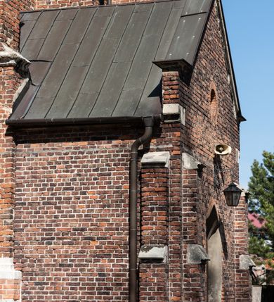 Zdjęcie nr 44: Kościół jest zlokalizowany na wzgórzu, w centrum wsi. Murowany z cegły, w wątku polskim, z zendrówką. Kościół jest orientowany, założony na planie prostokąta, jednonawowy, trójprzęsłowy, z dobudowanymi kruchtami od zachodu i południa. Prezbiterium oddzielone od nawy łukiem tęczowym, dwuprzęsłowe na planie prostokąta, zamknięte prostą ścianą, z dwukondygnacyjną przybudówką zakończoną trójbocznie. Nawa została przykryta sklepieniem sieciowym. Ściana południowa nawy przepruta trzema prostokątnymi oknami, zamkniętymi łukiem ostrym. Okna w nawie i prezbiterium dwudzielne, z sześcioma mniejszymi kwaterami. Przybudówka przy prezbiterium na parterze mieści zakrystię, a na piętrze składzik. Kruchta południowa sklepiona kolebką. Z kruchty do nawy prowadzi ostrołukowy, kamienny portal o dwóch archiwoltach. Kruchta zachodnia, obecnie kaplica św. Franciszka, sklepiona spłaszczoną, ukrytą kopułą na pendentywach. Ściana zachodnia kruchty przepruta dwoma ostrołukowymi oknami i ponad nimi okrągłym oknem. Od południa ostrołukowe wejście. Kościół o zróżnicowanej wysokości nawy i prezbiterium. Ściany opięte szkarpami. Na jednej trzeciej wysokości ścian oraz w zwieńczeniu nawy i prezbiterium profilowany gzyms. Od zachodu wklęsło-wypukły szczyt. Nawa, prezbiterium i dwie kruchty przykryte dachem dwuspadowym. Nad drugim przęsłem prezbiterium wieżyczka na sygnaturkę na planie ośmioboku, z profilowanym gzymsem i latarnią, zwieńczoną hełmem z kulą i krzyżem. Wejście do kościoła od południa i zachodu. Okna nawy i prezbiterium z kamiennym obramieniem. Nad wejściem do kruchty południowej formowany w cegle ostry łuk. Analogiczny łuk nad oknami w ścianie zachodniej i nad blendą w ścianie północnej. W przybudówce do prezbiterium dwie kondygnacje okien zamkniętych łukiem ostrym. W ścianie frontowej prostokątne wejście, a nad nim półkoliście zamknięta wnęka z grupą Ukrzyżowania. 


