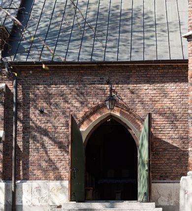 Zdjęcie nr 50: Kościół jest zlokalizowany na wzgórzu, w centrum wsi. Murowany z cegły, w wątku polskim, z zendrówką. Kościół jest orientowany, założony na planie prostokąta, jednonawowy, trójprzęsłowy, z dobudowanymi kruchtami od zachodu i południa. Prezbiterium oddzielone od nawy łukiem tęczowym, dwuprzęsłowe na planie prostokąta, zamknięte prostą ścianą, z dwukondygnacyjną przybudówką zakończoną trójbocznie. Nawa została przykryta sklepieniem sieciowym. Ściana południowa nawy przepruta trzema prostokątnymi oknami, zamkniętymi łukiem ostrym. Okna w nawie i prezbiterium dwudzielne, z sześcioma mniejszymi kwaterami. Przybudówka przy prezbiterium na parterze mieści zakrystię, a na piętrze składzik. Kruchta południowa sklepiona kolebką. Z kruchty do nawy prowadzi ostrołukowy, kamienny portal o dwóch archiwoltach. Kruchta zachodnia, obecnie kaplica św. Franciszka, sklepiona spłaszczoną, ukrytą kopułą na pendentywach. Ściana zachodnia kruchty przepruta dwoma ostrołukowymi oknami i ponad nimi okrągłym oknem. Od południa ostrołukowe wejście. Kościół o zróżnicowanej wysokości nawy i prezbiterium. Ściany opięte szkarpami. Na jednej trzeciej wysokości ścian oraz w zwieńczeniu nawy i prezbiterium profilowany gzyms. Od zachodu wklęsło-wypukły szczyt. Nawa, prezbiterium i dwie kruchty przykryte dachem dwuspadowym. Nad drugim przęsłem prezbiterium wieżyczka na sygnaturkę na planie ośmioboku, z profilowanym gzymsem i latarnią, zwieńczoną hełmem z kulą i krzyżem. Wejście do kościoła od południa i zachodu. Okna nawy i prezbiterium z kamiennym obramieniem. Nad wejściem do kruchty południowej formowany w cegle ostry łuk. Analogiczny łuk nad oknami w ścianie zachodniej i nad blendą w ścianie północnej. W przybudówce do prezbiterium dwie kondygnacje okien zamkniętych łukiem ostrym. W ścianie frontowej prostokątne wejście, a nad nim półkoliście zamknięta wnęka z grupą Ukrzyżowania. 


