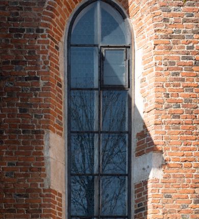 Zdjęcie nr 33: Kościół jest zlokalizowany na wzgórzu, w centrum wsi. Murowany z cegły, w wątku polskim, z zendrówką. Kościół jest orientowany, założony na planie prostokąta, jednonawowy, trójprzęsłowy, z dobudowanymi kruchtami od zachodu i południa. Prezbiterium oddzielone od nawy łukiem tęczowym, dwuprzęsłowe na planie prostokąta, zamknięte prostą ścianą, z dwukondygnacyjną przybudówką zakończoną trójbocznie. Nawa została przykryta sklepieniem sieciowym. Ściana południowa nawy przepruta trzema prostokątnymi oknami, zamkniętymi łukiem ostrym. Okna w nawie i prezbiterium dwudzielne, z sześcioma mniejszymi kwaterami. Przybudówka przy prezbiterium na parterze mieści zakrystię, a na piętrze składzik. Kruchta południowa sklepiona kolebką. Z kruchty do nawy prowadzi ostrołukowy, kamienny portal o dwóch archiwoltach. Kruchta zachodnia, obecnie kaplica św. Franciszka, sklepiona spłaszczoną, ukrytą kopułą na pendentywach. Ściana zachodnia kruchty przepruta dwoma ostrołukowymi oknami i ponad nimi okrągłym oknem. Od południa ostrołukowe wejście. Kościół o zróżnicowanej wysokości nawy i prezbiterium. Ściany opięte szkarpami. Na jednej trzeciej wysokości ścian oraz w zwieńczeniu nawy i prezbiterium profilowany gzyms. Od zachodu wklęsło-wypukły szczyt. Nawa, prezbiterium i dwie kruchty przykryte dachem dwuspadowym. Nad drugim przęsłem prezbiterium wieżyczka na sygnaturkę na planie ośmioboku, z profilowanym gzymsem i latarnią, zwieńczoną hełmem z kulą i krzyżem. Wejście do kościoła od południa i zachodu. Okna nawy i prezbiterium z kamiennym obramieniem. Nad wejściem do kruchty południowej formowany w cegle ostry łuk. Analogiczny łuk nad oknami w ścianie zachodniej i nad blendą w ścianie północnej. W przybudówce do prezbiterium dwie kondygnacje okien zamkniętych łukiem ostrym. W ścianie frontowej prostokątne wejście, a nad nim półkoliście zamknięta wnęka z grupą Ukrzyżowania. 


