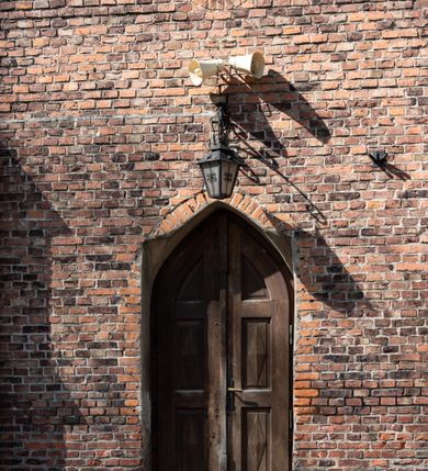 Zdjęcie nr 47: Kościół jest zlokalizowany na wzgórzu, w centrum wsi. Murowany z cegły, w wątku polskim, z zendrówką. Kościół jest orientowany, założony na planie prostokąta, jednonawowy, trójprzęsłowy, z dobudowanymi kruchtami od zachodu i południa. Prezbiterium oddzielone od nawy łukiem tęczowym, dwuprzęsłowe na planie prostokąta, zamknięte prostą ścianą, z dwukondygnacyjną przybudówką zakończoną trójbocznie. Nawa została przykryta sklepieniem sieciowym. Ściana południowa nawy przepruta trzema prostokątnymi oknami, zamkniętymi łukiem ostrym. Okna w nawie i prezbiterium dwudzielne, z sześcioma mniejszymi kwaterami. Przybudówka przy prezbiterium na parterze mieści zakrystię, a na piętrze składzik. Kruchta południowa sklepiona kolebką. Z kruchty do nawy prowadzi ostrołukowy, kamienny portal o dwóch archiwoltach. Kruchta zachodnia, obecnie kaplica św. Franciszka, sklepiona spłaszczoną, ukrytą kopułą na pendentywach. Ściana zachodnia kruchty przepruta dwoma ostrołukowymi oknami i ponad nimi okrągłym oknem. Od południa ostrołukowe wejście. Kościół o zróżnicowanej wysokości nawy i prezbiterium. Ściany opięte szkarpami. Na jednej trzeciej wysokości ścian oraz w zwieńczeniu nawy i prezbiterium profilowany gzyms. Od zachodu wklęsło-wypukły szczyt. Nawa, prezbiterium i dwie kruchty przykryte dachem dwuspadowym. Nad drugim przęsłem prezbiterium wieżyczka na sygnaturkę na planie ośmioboku, z profilowanym gzymsem i latarnią, zwieńczoną hełmem z kulą i krzyżem. Wejście do kościoła od południa i zachodu. Okna nawy i prezbiterium z kamiennym obramieniem. Nad wejściem do kruchty południowej formowany w cegle ostry łuk. Analogiczny łuk nad oknami w ścianie zachodniej i nad blendą w ścianie północnej. W przybudówce do prezbiterium dwie kondygnacje okien zamkniętych łukiem ostrym. W ścianie frontowej prostokątne wejście, a nad nim półkoliście zamknięta wnęka z grupą Ukrzyżowania. 


