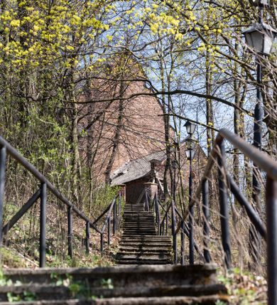 Zdjęcie nr 82: Kościół jest zlokalizowany na wzgórzu, w centrum wsi. Murowany z cegły, w wątku polskim, z zendrówką. Kościół jest orientowany, założony na planie prostokąta, jednonawowy, trójprzęsłowy, z dobudowanymi kruchtami od zachodu i południa. Prezbiterium oddzielone od nawy łukiem tęczowym, dwuprzęsłowe na planie prostokąta, zamknięte prostą ścianą, z dwukondygnacyjną przybudówką zakończoną trójbocznie. Nawa została przykryta sklepieniem sieciowym. Ściana południowa nawy przepruta trzema prostokątnymi oknami, zamkniętymi łukiem ostrym. Okna w nawie i prezbiterium dwudzielne, z sześcioma mniejszymi kwaterami. Przybudówka przy prezbiterium na parterze mieści zakrystię, a na piętrze składzik. Kruchta południowa sklepiona kolebką. Z kruchty do nawy prowadzi ostrołukowy, kamienny portal o dwóch archiwoltach. Kruchta zachodnia, obecnie kaplica św. Franciszka, sklepiona spłaszczoną, ukrytą kopułą na pendentywach. Ściana zachodnia kruchty przepruta dwoma ostrołukowymi oknami i ponad nimi okrągłym oknem. Od południa ostrołukowe wejście. Kościół o zróżnicowanej wysokości nawy i prezbiterium. Ściany opięte szkarpami. Na jednej trzeciej wysokości ścian oraz w zwieńczeniu nawy i prezbiterium profilowany gzyms. Od zachodu wklęsło-wypukły szczyt. Nawa, prezbiterium i dwie kruchty przykryte dachem dwuspadowym. Nad drugim przęsłem prezbiterium wieżyczka na sygnaturkę na planie ośmioboku, z profilowanym gzymsem i latarnią, zwieńczoną hełmem z kulą i krzyżem. Wejście do kościoła od południa i zachodu. Okna nawy i prezbiterium z kamiennym obramieniem. Nad wejściem do kruchty południowej formowany w cegle ostry łuk. Analogiczny łuk nad oknami w ścianie zachodniej i nad blendą w ścianie północnej. W przybudówce do prezbiterium dwie kondygnacje okien zamkniętych łukiem ostrym. W ścianie frontowej prostokątne wejście, a nad nim półkoliście zamknięta wnęka z grupą Ukrzyżowania. 


