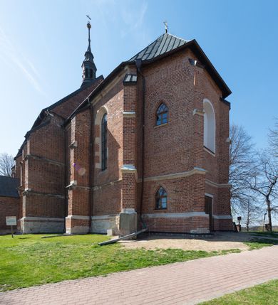 Zdjęcie nr 18: Kościół jest zlokalizowany na wzgórzu, w centrum wsi. Murowany z cegły, w wątku polskim, z zendrówką. Kościół jest orientowany, założony na planie prostokąta, jednonawowy, trójprzęsłowy, z dobudowanymi kruchtami od zachodu i południa. Prezbiterium oddzielone od nawy łukiem tęczowym, dwuprzęsłowe na planie prostokąta, zamknięte prostą ścianą, z dwukondygnacyjną przybudówką zakończoną trójbocznie. Nawa została przykryta sklepieniem sieciowym. Ściana południowa nawy przepruta trzema prostokątnymi oknami, zamkniętymi łukiem ostrym. Okna w nawie i prezbiterium dwudzielne, z sześcioma mniejszymi kwaterami. Przybudówka przy prezbiterium na parterze mieści zakrystię, a na piętrze składzik. Kruchta południowa sklepiona kolebką. Z kruchty do nawy prowadzi ostrołukowy, kamienny portal o dwóch archiwoltach. Kruchta zachodnia, obecnie kaplica św. Franciszka, sklepiona spłaszczoną, ukrytą kopułą na pendentywach. Ściana zachodnia kruchty przepruta dwoma ostrołukowymi oknami i ponad nimi okrągłym oknem. Od południa ostrołukowe wejście. Kościół o zróżnicowanej wysokości nawy i prezbiterium. Ściany opięte szkarpami. Na jednej trzeciej wysokości ścian oraz w zwieńczeniu nawy i prezbiterium profilowany gzyms. Od zachodu wklęsło-wypukły szczyt. Nawa, prezbiterium i dwie kruchty przykryte dachem dwuspadowym. Nad drugim przęsłem prezbiterium wieżyczka na sygnaturkę na planie ośmioboku, z profilowanym gzymsem i latarnią, zwieńczoną hełmem z kulą i krzyżem. Wejście do kościoła od południa i zachodu. Okna nawy i prezbiterium z kamiennym obramieniem. Nad wejściem do kruchty południowej formowany w cegle ostry łuk. Analogiczny łuk nad oknami w ścianie zachodniej i nad blendą w ścianie północnej. W przybudówce do prezbiterium dwie kondygnacje okien zamkniętych łukiem ostrym. W ścianie frontowej prostokątne wejście, a nad nim półkoliście zamknięta wnęka z grupą Ukrzyżowania. 


