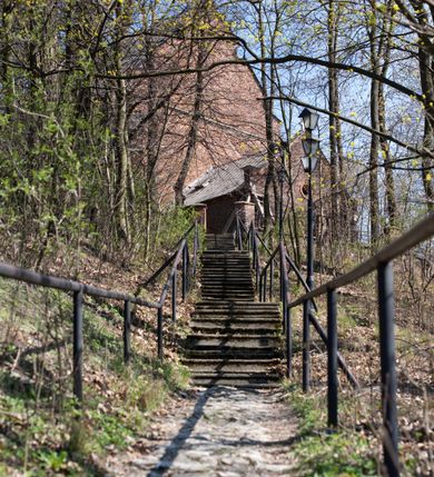 Zdjęcie nr 83: Kościół jest zlokalizowany na wzgórzu, w centrum wsi. Murowany z cegły, w wątku polskim, z zendrówką. Kościół jest orientowany, założony na planie prostokąta, jednonawowy, trójprzęsłowy, z dobudowanymi kruchtami od zachodu i południa. Prezbiterium oddzielone od nawy łukiem tęczowym, dwuprzęsłowe na planie prostokąta, zamknięte prostą ścianą, z dwukondygnacyjną przybudówką zakończoną trójbocznie. Nawa została przykryta sklepieniem sieciowym. Ściana południowa nawy przepruta trzema prostokątnymi oknami, zamkniętymi łukiem ostrym. Okna w nawie i prezbiterium dwudzielne, z sześcioma mniejszymi kwaterami. Przybudówka przy prezbiterium na parterze mieści zakrystię, a na piętrze składzik. Kruchta południowa sklepiona kolebką. Z kruchty do nawy prowadzi ostrołukowy, kamienny portal o dwóch archiwoltach. Kruchta zachodnia, obecnie kaplica św. Franciszka, sklepiona spłaszczoną, ukrytą kopułą na pendentywach. Ściana zachodnia kruchty przepruta dwoma ostrołukowymi oknami i ponad nimi okrągłym oknem. Od południa ostrołukowe wejście. Kościół o zróżnicowanej wysokości nawy i prezbiterium. Ściany opięte szkarpami. Na jednej trzeciej wysokości ścian oraz w zwieńczeniu nawy i prezbiterium profilowany gzyms. Od zachodu wklęsło-wypukły szczyt. Nawa, prezbiterium i dwie kruchty przykryte dachem dwuspadowym. Nad drugim przęsłem prezbiterium wieżyczka na sygnaturkę na planie ośmioboku, z profilowanym gzymsem i latarnią, zwieńczoną hełmem z kulą i krzyżem. Wejście do kościoła od południa i zachodu. Okna nawy i prezbiterium z kamiennym obramieniem. Nad wejściem do kruchty południowej formowany w cegle ostry łuk. Analogiczny łuk nad oknami w ścianie zachodniej i nad blendą w ścianie północnej. W przybudówce do prezbiterium dwie kondygnacje okien zamkniętych łukiem ostrym. W ścianie frontowej prostokątne wejście, a nad nim półkoliście zamknięta wnęka z grupą Ukrzyżowania. 


