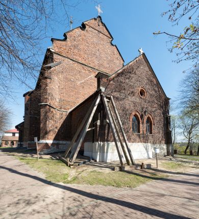 Zdjęcie nr 51: Kościół jest zlokalizowany na wzgórzu, w centrum wsi. Murowany z cegły, w wątku polskim, z zendrówką. Kościół jest orientowany, założony na planie prostokąta, jednonawowy, trójprzęsłowy, z dobudowanymi kruchtami od zachodu i południa. Prezbiterium oddzielone od nawy łukiem tęczowym, dwuprzęsłowe na planie prostokąta, zamknięte prostą ścianą, z dwukondygnacyjną przybudówką zakończoną trójbocznie. Nawa została przykryta sklepieniem sieciowym. Ściana południowa nawy przepruta trzema prostokątnymi oknami, zamkniętymi łukiem ostrym. Okna w nawie i prezbiterium dwudzielne, z sześcioma mniejszymi kwaterami. Przybudówka przy prezbiterium na parterze mieści zakrystię, a na piętrze składzik. Kruchta południowa sklepiona kolebką. Z kruchty do nawy prowadzi ostrołukowy, kamienny portal o dwóch archiwoltach. Kruchta zachodnia, obecnie kaplica św. Franciszka, sklepiona spłaszczoną, ukrytą kopułą na pendentywach. Ściana zachodnia kruchty przepruta dwoma ostrołukowymi oknami i ponad nimi okrągłym oknem. Od południa ostrołukowe wejście. Kościół o zróżnicowanej wysokości nawy i prezbiterium. Ściany opięte szkarpami. Na jednej trzeciej wysokości ścian oraz w zwieńczeniu nawy i prezbiterium profilowany gzyms. Od zachodu wklęsło-wypukły szczyt. Nawa, prezbiterium i dwie kruchty przykryte dachem dwuspadowym. Nad drugim przęsłem prezbiterium wieżyczka na sygnaturkę na planie ośmioboku, z profilowanym gzymsem i latarnią, zwieńczoną hełmem z kulą i krzyżem. Wejście do kościoła od południa i zachodu. Okna nawy i prezbiterium z kamiennym obramieniem. Nad wejściem do kruchty południowej formowany w cegle ostry łuk. Analogiczny łuk nad oknami w ścianie zachodniej i nad blendą w ścianie północnej. W przybudówce do prezbiterium dwie kondygnacje okien zamkniętych łukiem ostrym. W ścianie frontowej prostokątne wejście, a nad nim półkoliście zamknięta wnęka z grupą Ukrzyżowania. 


