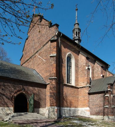 Zdjęcie nr 40: Kościół jest zlokalizowany na wzgórzu, w centrum wsi. Murowany z cegły, w wątku polskim, z zendrówką. Kościół jest orientowany, założony na planie prostokąta, jednonawowy, trójprzęsłowy, z dobudowanymi kruchtami od zachodu i południa. Prezbiterium oddzielone od nawy łukiem tęczowym, dwuprzęsłowe na planie prostokąta, zamknięte prostą ścianą, z dwukondygnacyjną przybudówką zakończoną trójbocznie. Nawa została przykryta sklepieniem sieciowym. Ściana południowa nawy przepruta trzema prostokątnymi oknami, zamkniętymi łukiem ostrym. Okna w nawie i prezbiterium dwudzielne, z sześcioma mniejszymi kwaterami. Przybudówka przy prezbiterium na parterze mieści zakrystię, a na piętrze składzik. Kruchta południowa sklepiona kolebką. Z kruchty do nawy prowadzi ostrołukowy, kamienny portal o dwóch archiwoltach. Kruchta zachodnia, obecnie kaplica św. Franciszka, sklepiona spłaszczoną, ukrytą kopułą na pendentywach. Ściana zachodnia kruchty przepruta dwoma ostrołukowymi oknami i ponad nimi okrągłym oknem. Od południa ostrołukowe wejście. Kościół o zróżnicowanej wysokości nawy i prezbiterium. Ściany opięte szkarpami. Na jednej trzeciej wysokości ścian oraz w zwieńczeniu nawy i prezbiterium profilowany gzyms. Od zachodu wklęsło-wypukły szczyt. Nawa, prezbiterium i dwie kruchty przykryte dachem dwuspadowym. Nad drugim przęsłem prezbiterium wieżyczka na sygnaturkę na planie ośmioboku, z profilowanym gzymsem i latarnią, zwieńczoną hełmem z kulą i krzyżem. Wejście do kościoła od południa i zachodu. Okna nawy i prezbiterium z kamiennym obramieniem. Nad wejściem do kruchty południowej formowany w cegle ostry łuk. Analogiczny łuk nad oknami w ścianie zachodniej i nad blendą w ścianie północnej. W przybudówce do prezbiterium dwie kondygnacje okien zamkniętych łukiem ostrym. W ścianie frontowej prostokątne wejście, a nad nim półkoliście zamknięta wnęka z grupą Ukrzyżowania. 


