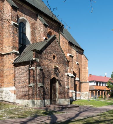 Zdjęcie nr 42: Kościół jest zlokalizowany na wzgórzu, w centrum wsi. Murowany z cegły, w wątku polskim, z zendrówką. Kościół jest orientowany, założony na planie prostokąta, jednonawowy, trójprzęsłowy, z dobudowanymi kruchtami od zachodu i południa. Prezbiterium oddzielone od nawy łukiem tęczowym, dwuprzęsłowe na planie prostokąta, zamknięte prostą ścianą, z dwukondygnacyjną przybudówką zakończoną trójbocznie. Nawa została przykryta sklepieniem sieciowym. Ściana południowa nawy przepruta trzema prostokątnymi oknami, zamkniętymi łukiem ostrym. Okna w nawie i prezbiterium dwudzielne, z sześcioma mniejszymi kwaterami. Przybudówka przy prezbiterium na parterze mieści zakrystię, a na piętrze składzik. Kruchta południowa sklepiona kolebką. Z kruchty do nawy prowadzi ostrołukowy, kamienny portal o dwóch archiwoltach. Kruchta zachodnia, obecnie kaplica św. Franciszka, sklepiona spłaszczoną, ukrytą kopułą na pendentywach. Ściana zachodnia kruchty przepruta dwoma ostrołukowymi oknami i ponad nimi okrągłym oknem. Od południa ostrołukowe wejście. Kościół o zróżnicowanej wysokości nawy i prezbiterium. Ściany opięte szkarpami. Na jednej trzeciej wysokości ścian oraz w zwieńczeniu nawy i prezbiterium profilowany gzyms. Od zachodu wklęsło-wypukły szczyt. Nawa, prezbiterium i dwie kruchty przykryte dachem dwuspadowym. Nad drugim przęsłem prezbiterium wieżyczka na sygnaturkę na planie ośmioboku, z profilowanym gzymsem i latarnią, zwieńczoną hełmem z kulą i krzyżem. Wejście do kościoła od południa i zachodu. Okna nawy i prezbiterium z kamiennym obramieniem. Nad wejściem do kruchty południowej formowany w cegle ostry łuk. Analogiczny łuk nad oknami w ścianie zachodniej i nad blendą w ścianie północnej. W przybudówce do prezbiterium dwie kondygnacje okien zamkniętych łukiem ostrym. W ścianie frontowej prostokątne wejście, a nad nim półkoliście zamknięta wnęka z grupą Ukrzyżowania. 


