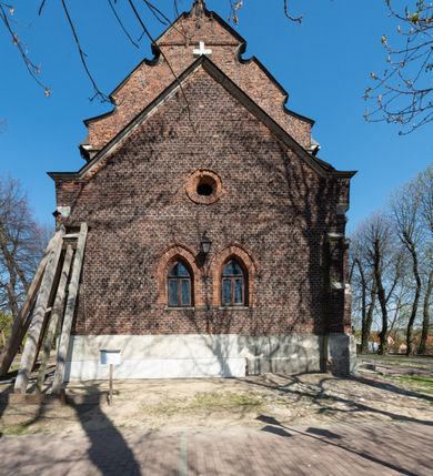 Zdjęcie nr 54: Kościół jest zlokalizowany na wzgórzu, w centrum wsi. Murowany z cegły, w wątku polskim, z zendrówką. Kościół jest orientowany, założony na planie prostokąta, jednonawowy, trójprzęsłowy, z dobudowanymi kruchtami od zachodu i południa. Prezbiterium oddzielone od nawy łukiem tęczowym, dwuprzęsłowe na planie prostokąta, zamknięte prostą ścianą, z dwukondygnacyjną przybudówką zakończoną trójbocznie. Nawa została przykryta sklepieniem sieciowym. Ściana południowa nawy przepruta trzema prostokątnymi oknami, zamkniętymi łukiem ostrym. Okna w nawie i prezbiterium dwudzielne, z sześcioma mniejszymi kwaterami. Przybudówka przy prezbiterium na parterze mieści zakrystię, a na piętrze składzik. Kruchta południowa sklepiona kolebką. Z kruchty do nawy prowadzi ostrołukowy, kamienny portal o dwóch archiwoltach. Kruchta zachodnia, obecnie kaplica św. Franciszka, sklepiona spłaszczoną, ukrytą kopułą na pendentywach. Ściana zachodnia kruchty przepruta dwoma ostrołukowymi oknami i ponad nimi okrągłym oknem. Od południa ostrołukowe wejście. Kościół o zróżnicowanej wysokości nawy i prezbiterium. Ściany opięte szkarpami. Na jednej trzeciej wysokości ścian oraz w zwieńczeniu nawy i prezbiterium profilowany gzyms. Od zachodu wklęsło-wypukły szczyt. Nawa, prezbiterium i dwie kruchty przykryte dachem dwuspadowym. Nad drugim przęsłem prezbiterium wieżyczka na sygnaturkę na planie ośmioboku, z profilowanym gzymsem i latarnią, zwieńczoną hełmem z kulą i krzyżem. Wejście do kościoła od południa i zachodu. Okna nawy i prezbiterium z kamiennym obramieniem. Nad wejściem do kruchty południowej formowany w cegle ostry łuk. Analogiczny łuk nad oknami w ścianie zachodniej i nad blendą w ścianie północnej. W przybudówce do prezbiterium dwie kondygnacje okien zamkniętych łukiem ostrym. W ścianie frontowej prostokątne wejście, a nad nim półkoliście zamknięta wnęka z grupą Ukrzyżowania. 



