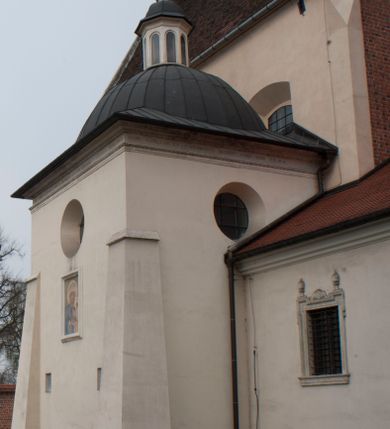 Zdjęcie nr 1: Kaplica pod wezwaniem Najświętszej Marii Panny i Wszystkich Świętych przylega do kościoła od południa, do pierwszego przęsła nawy, z którą komunikuje się za pomocą półkoliście zamkniętej arkady. Zbudowana została na planie kwadratu. Nakryto ją półsferyczną czaszą na pendentywach i zwieńczono latarnią. Wnętrze artykułowano za pomocą ślepej arkady z pilastrami i archiwoltami, ozdobionymi rzeźbioną dekoracją roślinną i kasetonami z rozetami w podłuczu. Ściany kaplicy zamyka wydatne belkowanie z fryzem i łacińską inskrypcją: "DEVS MEVS ET OMNIA / DILEXI DOMINE DECOREM DOMVS / TUAE ET LOCUM HABITATIONIS GLORAE TUAE PSAL(MUS) XXV". Na czterech pendentywach umieszczono stiukowe kartusze, z czego dwa od strony wschodniej są są puste, a dwa od strony zachodniej wypełniają herby skwadrowane: Gryf, Kotwicz, Kotwicz, Zabawa i Jastrzębiec, Nowina, Gozdawa, Pobóg. Wnętrze doświetlają trzy takie same okulusy umieszczone na każdej ze ścian. Czwarty okulus w ścianie północnej jest zaślepiony. Glify okulusów dekorowane są kasetonami z rozetami. Ściany kaplicy oraz wnętrze kopuły i latarni pokrywa polichromia figuralna. Po arkadą na ścianie wschodniej zawieszono obraz Matki Boskiej z Dzieciątkiem w bogato rzeźbionej roślinno-kwiatowej ramie zwieńczonej godłem z dwiema skrzyżowanymi laskami marszałkowskimi. Pod obrazem znajduje się nagrobek dziecięcy Jana Czuryły (zm. 1560) w formie płaskorzeźbionej, prostokątnej płyty z wyobrażeniem zmarłego. Nad płytą zlokalizowano mniejszą z inskrypcją odnoszącą się do zmarłego. Z kolei wnętrze arkady z herbem Gryf w kluczu na ścianie południowej wypełnia trójosiowy nagrobek Branickich z półokrągłym zwieńczeniem. Natomiast w arkadzie zachodniej wyobrażono scenę Zdjęcia z krzyża w formie malowidła ściennego. Wyposażenie wnętrza dopełniają dwie drewniane ławy kościelne. Ściany zewnętrzne wspierają dwie niskie przypory widoczne w narożach kaplicy. Całość zakończona jest belkowaniem z fryzem zawierającym inskrypcję: "AD LAVDEM DEI OPT(IMO) M(AXIMO) BEATEQUE GENITRICIS MARIAE VIRGINIS ET OMNIUM SANCTORU(M) HONOREM JOHANNES A RVSCZA BRANICZKI VENATOR CRACOVIEN(SIS) ET CAPITANEVS NIEPOLONICEN(SIS) - HANC CAPELLAM EX FVNDAMENTIS EREXIT ANNO D(OMI)NI 1596". Na ścianie południowej widnieje półokrągła blenda z malowanym przedstawieniem Matki Boskiej Częstochowskiej. Latarnię kaplicy wieńczy głowica z czterema maskami maszkaronów, na której wspiera się złocona kula z krzyżem.