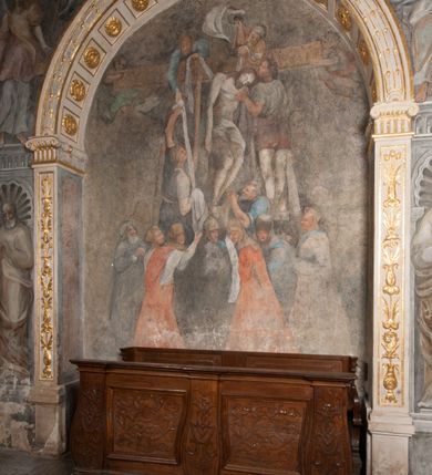 Zdjęcie nr 102: Kaplica pod wezwaniem Najświętszej Marii Panny i Wszystkich Świętych przylega do kościoła od południa, do pierwszego przęsła nawy, z którą komunikuje się za pomocą półkoliście zamkniętej arkady. Zbudowana została na planie kwadratu. Nakryto ją półsferyczną czaszą na pendentywach i zwieńczono latarnią. Wnętrze artykułowano za pomocą ślepej arkady z pilastrami i archiwoltami, ozdobionymi rzeźbioną dekoracją roślinną i kasetonami z rozetami w podłuczu. Ściany kaplicy zamyka wydatne belkowanie z fryzem i łacińską inskrypcją: &quot;DEVS MEVS ET OMNIA / DILEXI DOMINE DECOREM DOMVS / TUAE ET LOCUM HABITATIONIS GLORAE TUAE PSAL(MUS) XXV&quot;. Na czterech pendentywach umieszczono stiukowe kartusze, z czego dwa od strony wschodniej są są puste, a dwa od strony zachodniej wypełniają herby skwadrowane: Gryf, Kotwicz, Kotwicz, Zabawa i Jastrzębiec, Nowina, Gozdawa, Pobóg. Wnętrze doświetlają trzy takie same okulusy umieszczone na każdej ze ścian. Czwarty okulus w ścianie północnej jest zaślepiony. Glify okulusów dekorowane są kasetonami z rozetami. Ściany kaplicy oraz wnętrze kopuły i latarni pokrywa polichromia figuralna. Po arkadą na ścianie wschodniej zawieszono obraz Matki Boskiej z Dzieciątkiem w bogato rzeźbionej roślinno-kwiatowej ramie zwieńczonej godłem z dwiema skrzyżowanymi laskami marszałkowskimi. Pod obrazem znajduje się nagrobek dziecięcy Jana Czuryły (zm. 1560) w formie płaskorzeźbionej, prostokątnej płyty z wyobrażeniem zmarłego. Nad płytą zlokalizowano mniejszą z inskrypcją odnoszącą się do zmarłego. Z kolei wnętrze arkady z herbem Gryf w kluczu na ścianie południowej wypełnia trójosiowy nagrobek Branickich z półokrągłym zwieńczeniem. Natomiast w arkadzie zachodniej wyobrażono scenę Zdjęcia z krzyża w formie malowidła ściennego. Wyposażenie wnętrza dopełniają dwie drewniane ławy kościelne. Ściany zewnętrzne wspierają dwie niskie przypory widoczne w narożach kaplicy. Całość zakończona jest belkowaniem z fryzem zawierającym inskrypcję: &quot;AD LAVDEM DEI OPT(IMO) M(AXIMO) BEATEQUE GENITRICIS MARIAE VIRGINIS ET OMNIUM SANCTORU(M) HONOREM JOHANNES A RVSCZA BRANICZKI VENATOR CRACOVIEN(SIS) ET CAPITANEVS NIEPOLONICEN(SIS) - HANC CAPELLAM EX FVNDAMENTIS EREXIT ANNO D(OMI)NI 1596&quot;. Na ścianie południowej widnieje półokrągła blenda z malowanym przedstawieniem Matki Boskiej Częstochowskiej. Latarnię kaplicy wieńczy głowica z czterema maskami maszkaronów, na której wspiera się złocona kula z krzyżem.