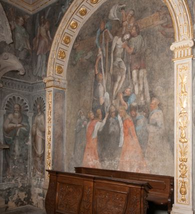 Zdjęcie nr 103: Kaplica pod wezwaniem Najświętszej Marii Panny i Wszystkich Świętych przylega do kościoła od południa, do pierwszego przęsła nawy, z którą komunikuje się za pomocą półkoliście zamkniętej arkady. Zbudowana została na planie kwadratu. Nakryto ją półsferyczną czaszą na pendentywach i zwieńczono latarnią. Wnętrze artykułowano za pomocą ślepej arkady z pilastrami i archiwoltami, ozdobionymi rzeźbioną dekoracją roślinną i kasetonami z rozetami w podłuczu. Ściany kaplicy zamyka wydatne belkowanie z fryzem i łacińską inskrypcją: "DEVS MEVS ET OMNIA / DILEXI DOMINE DECOREM DOMVS / TUAE ET LOCUM HABITATIONIS GLORAE TUAE PSAL(MUS) XXV". Na czterech pendentywach umieszczono stiukowe kartusze, z czego dwa od strony wschodniej są są puste, a dwa od strony zachodniej wypełniają herby skwadrowane: Gryf, Kotwicz, Kotwicz, Zabawa i Jastrzębiec, Nowina, Gozdawa, Pobóg. Wnętrze doświetlają trzy takie same okulusy umieszczone na każdej ze ścian. Czwarty okulus w ścianie północnej jest zaślepiony. Glify okulusów dekorowane są kasetonami z rozetami. Ściany kaplicy oraz wnętrze kopuły i latarni pokrywa polichromia figuralna. Po arkadą na ścianie wschodniej zawieszono obraz Matki Boskiej z Dzieciątkiem w bogato rzeźbionej roślinno-kwiatowej ramie zwieńczonej godłem z dwiema skrzyżowanymi laskami marszałkowskimi. Pod obrazem znajduje się nagrobek dziecięcy Jana Czuryły (zm. 1560) w formie płaskorzeźbionej, prostokątnej płyty z wyobrażeniem zmarłego. Nad płytą zlokalizowano mniejszą z inskrypcją odnoszącą się do zmarłego. Z kolei wnętrze arkady z herbem Gryf w kluczu na ścianie południowej wypełnia trójosiowy nagrobek Branickich z półokrągłym zwieńczeniem. Natomiast w arkadzie zachodniej wyobrażono scenę Zdjęcia z krzyża w formie malowidła ściennego. Wyposażenie wnętrza dopełniają dwie drewniane ławy kościelne. Ściany zewnętrzne wspierają dwie niskie przypory widoczne w narożach kaplicy. Całość zakończona jest belkowaniem z fryzem zawierającym inskrypcję: "AD LAVDEM DEI OPT(IMO) M(AXIMO) BEATEQUE GENITRICIS MARIAE VIRGINIS ET OMNIUM SANCTORU(M) HONOREM JOHANNES A RVSCZA BRANICZKI VENATOR CRACOVIEN(SIS) ET CAPITANEVS NIEPOLONICEN(SIS) - HANC CAPELLAM EX FVNDAMENTIS EREXIT ANNO D(OMI)NI 1596". Na ścianie południowej widnieje półokrągła blenda z malowanym przedstawieniem Matki Boskiej Częstochowskiej. Latarnię kaplicy wieńczy głowica z czterema maskami maszkaronów, na której wspiera się złocona kula z krzyżem.