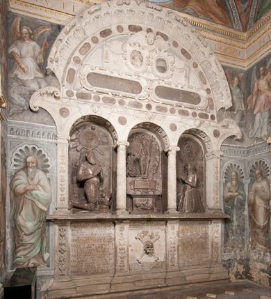 Zdjęcie nr 107: Kaplica pod wezwaniem Najświętszej Marii Panny i Wszystkich Świętych przylega do kościoła od południa, do pierwszego przęsła nawy, z którą komunikuje się za pomocą półkoliście zamkniętej arkady. Zbudowana została na planie kwadratu. Nakryto ją półsferyczną czaszą na pendentywach i zwieńczono latarnią. Wnętrze artykułowano za pomocą ślepej arkady z pilastrami i archiwoltami, ozdobionymi rzeźbioną dekoracją roślinną i kasetonami z rozetami w podłuczu. Ściany kaplicy zamyka wydatne belkowanie z fryzem i łacińską inskrypcją: "DEVS MEVS ET OMNIA / DILEXI DOMINE DECOREM DOMVS / TUAE ET LOCUM HABITATIONIS GLORAE TUAE PSAL(MUS) XXV". Na czterech pendentywach umieszczono stiukowe kartusze, z czego dwa od strony wschodniej są są puste, a dwa od strony zachodniej wypełniają herby skwadrowane: Gryf, Kotwicz, Kotwicz, Zabawa i Jastrzębiec, Nowina, Gozdawa, Pobóg. Wnętrze doświetlają trzy takie same okulusy umieszczone na każdej ze ścian. Czwarty okulus w ścianie północnej jest zaślepiony. Glify okulusów dekorowane są kasetonami z rozetami. Ściany kaplicy oraz wnętrze kopuły i latarni pokrywa polichromia figuralna. Po arkadą na ścianie wschodniej zawieszono obraz Matki Boskiej z Dzieciątkiem w bogato rzeźbionej roślinno-kwiatowej ramie zwieńczonej godłem z dwiema skrzyżowanymi laskami marszałkowskimi. Pod obrazem znajduje się nagrobek dziecięcy Jana Czuryły (zm. 1560) w formie płaskorzeźbionej, prostokątnej płyty z wyobrażeniem zmarłego. Nad płytą zlokalizowano mniejszą z inskrypcją odnoszącą się do zmarłego. Z kolei wnętrze arkady z herbem Gryf w kluczu na ścianie południowej wypełnia trójosiowy nagrobek Branickich z półokrągłym zwieńczeniem. Natomiast w arkadzie zachodniej wyobrażono scenę Zdjęcia z krzyża w formie malowidła ściennego. Wyposażenie wnętrza dopełniają dwie drewniane ławy kościelne. Ściany zewnętrzne wspierają dwie niskie przypory widoczne w narożach kaplicy. Całość zakończona jest belkowaniem z fryzem zawierającym inskrypcję: "AD LAVDEM DEI OPT(IMO) M(AXIMO) BEATEQUE GENITRICIS MARIAE VIRGINIS ET OMNIUM SANCTORU(M) HONOREM JOHANNES A RVSCZA BRANICZKI VENATOR CRACOVIEN(SIS) ET CAPITANEVS NIEPOLONICEN(SIS) - HANC CAPELLAM EX FVNDAMENTIS EREXIT ANNO D(OMI)NI 1596". Na ścianie południowej widnieje półokrągła blenda z malowanym przedstawieniem Matki Boskiej Częstochowskiej. Latarnię kaplicy wieńczy głowica z czterema maskami maszkaronów, na której wspiera się złocona kula z krzyżem.