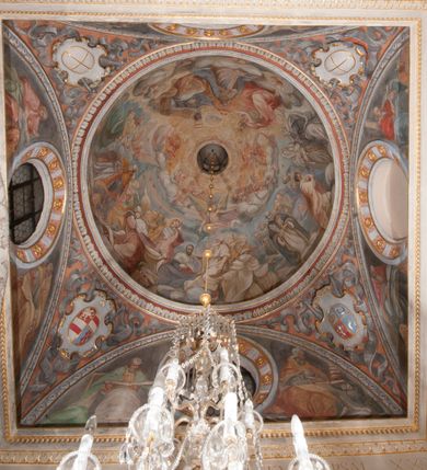 Zdjęcie nr 111: Kaplica pod wezwaniem Najświętszej Marii Panny i Wszystkich Świętych przylega do kościoła od południa, do pierwszego przęsła nawy, z którą komunikuje się za pomocą półkoliście zamkniętej arkady. Zbudowana została na planie kwadratu. Nakryto ją półsferyczną czaszą na pendentywach i zwieńczono latarnią. Wnętrze artykułowano za pomocą ślepej arkady z pilastrami i archiwoltami, ozdobionymi rzeźbioną dekoracją roślinną i kasetonami z rozetami w podłuczu. Ściany kaplicy zamyka wydatne belkowanie z fryzem i łacińską inskrypcją: &quot;DEVS MEVS ET OMNIA / DILEXI DOMINE DECOREM DOMVS / TUAE ET LOCUM HABITATIONIS GLORAE TUAE PSAL(MUS) XXV&quot;. Na czterech pendentywach umieszczono stiukowe kartusze, z czego dwa od strony wschodniej są są puste, a dwa od strony zachodniej wypełniają herby skwadrowane: Gryf, Kotwicz, Kotwicz, Zabawa i Jastrzębiec, Nowina, Gozdawa, Pobóg. Wnętrze doświetlają trzy takie same okulusy umieszczone na każdej ze ścian. Czwarty okulus w ścianie północnej jest zaślepiony. Glify okulusów dekorowane są kasetonami z rozetami. Ściany kaplicy oraz wnętrze kopuły i latarni pokrywa polichromia figuralna. Po arkadą na ścianie wschodniej zawieszono obraz Matki Boskiej z Dzieciątkiem w bogato rzeźbionej roślinno-kwiatowej ramie zwieńczonej godłem z dwiema skrzyżowanymi laskami marszałkowskimi. Pod obrazem znajduje się nagrobek dziecięcy Jana Czuryły (zm. 1560) w formie płaskorzeźbionej, prostokątnej płyty z wyobrażeniem zmarłego. Nad płytą zlokalizowano mniejszą z inskrypcją odnoszącą się do zmarłego. Z kolei wnętrze arkady z herbem Gryf w kluczu na ścianie południowej wypełnia trójosiowy nagrobek Branickich z półokrągłym zwieńczeniem. Natomiast w arkadzie zachodniej wyobrażono scenę Zdjęcia z krzyża w formie malowidła ściennego. Wyposażenie wnętrza dopełniają dwie drewniane ławy kościelne. Ściany zewnętrzne wspierają dwie niskie przypory widoczne w narożach kaplicy. Całość zakończona jest belkowaniem z fryzem zawierającym inskrypcję: &quot;AD LAVDEM DEI OPT(IMO) M(AXIMO) BEATEQUE GENITRICIS MARIAE VIRGINIS ET OMNIUM SANCTORU(M) HONOREM JOHANNES A RVSCZA BRANICZKI VENATOR CRACOVIEN(SIS) ET CAPITANEVS NIEPOLONICEN(SIS) - HANC CAPELLAM EX FVNDAMENTIS EREXIT ANNO D(OMI)NI 1596&quot;. Na ścianie południowej widnieje półokrągła blenda z malowanym przedstawieniem Matki Boskiej Częstochowskiej. Latarnię kaplicy wieńczy głowica z czterema maskami maszkaronów, na której wspiera się złocona kula z krzyżem.