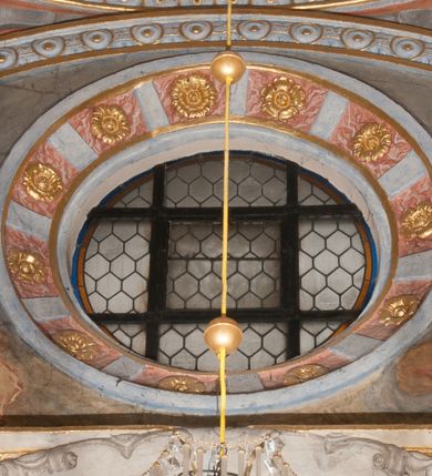 Zdjęcie nr 13: Kaplica pod wezwaniem Najświętszej Marii Panny i Wszystkich Świętych przylega do kościoła od południa, do pierwszego przęsła nawy, z którą komunikuje się za pomocą półkoliście zamkniętej arkady. Zbudowana została na planie kwadratu. Nakryto ją półsferyczną czaszą na pendentywach i zwieńczono latarnią. Wnętrze artykułowano za pomocą ślepej arkady z pilastrami i archiwoltami, ozdobionymi rzeźbioną dekoracją roślinną i kasetonami z rozetami w podłuczu. Ściany kaplicy zamyka wydatne belkowanie z fryzem i łacińską inskrypcją: "DEVS MEVS ET OMNIA / DILEXI DOMINE DECOREM DOMVS / TUAE ET LOCUM HABITATIONIS GLORAE TUAE PSAL(MUS) XXV". Na czterech pendentywach umieszczono stiukowe kartusze, z czego dwa od strony wschodniej są są puste, a dwa od strony zachodniej wypełniają herby skwadrowane: Gryf, Kotwicz, Kotwicz, Zabawa i Jastrzębiec, Nowina, Gozdawa, Pobóg. Wnętrze doświetlają trzy takie same okulusy umieszczone na każdej ze ścian. Czwarty okulus w ścianie północnej jest zaślepiony. Glify okulusów dekorowane są kasetonami z rozetami. Ściany kaplicy oraz wnętrze kopuły i latarni pokrywa polichromia figuralna. Po arkadą na ścianie wschodniej zawieszono obraz Matki Boskiej z Dzieciątkiem w bogato rzeźbionej roślinno-kwiatowej ramie zwieńczonej godłem z dwiema skrzyżowanymi laskami marszałkowskimi. Pod obrazem znajduje się nagrobek dziecięcy Jana Czuryły (zm. 1560) w formie płaskorzeźbionej, prostokątnej płyty z wyobrażeniem zmarłego. Nad płytą zlokalizowano mniejszą z inskrypcją odnoszącą się do zmarłego. Z kolei wnętrze arkady z herbem Gryf w kluczu na ścianie południowej wypełnia trójosiowy nagrobek Branickich z półokrągłym zwieńczeniem. Natomiast w arkadzie zachodniej wyobrażono scenę Zdjęcia z krzyża w formie malowidła ściennego. Wyposażenie wnętrza dopełniają dwie drewniane ławy kościelne. Ściany zewnętrzne wspierają dwie niskie przypory widoczne w narożach kaplicy. Całość zakończona jest belkowaniem z fryzem zawierającym inskrypcję: "AD LAVDEM DEI OPT(IMO) M(AXIMO) BEATEQUE GENITRICIS MARIAE VIRGINIS ET OMNIUM SANCTORU(M) HONOREM JOHANNES A RVSCZA BRANICZKI VENATOR CRACOVIEN(SIS) ET CAPITANEVS NIEPOLONICEN(SIS) - HANC CAPELLAM EX FVNDAMENTIS EREXIT ANNO D(OMI)NI 1596". Na ścianie południowej widnieje półokrągła blenda z malowanym przedstawieniem Matki Boskiej Częstochowskiej. Latarnię kaplicy wieńczy głowica z czterema maskami maszkaronów, na której wspiera się złocona kula z krzyżem.