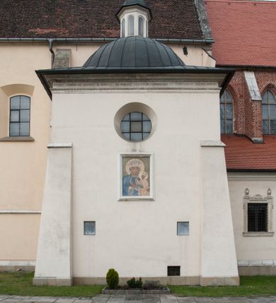 Zdjęcie nr 56: Kaplica pod wezwaniem Najświętszej Marii Panny i Wszystkich Świętych przylega do kościoła od południa, do pierwszego przęsła nawy, z którą komunikuje się za pomocą półkoliście zamkniętej arkady. Zbudowana została na planie kwadratu. Nakryto ją półsferyczną czaszą na pendentywach i zwieńczono latarnią. Wnętrze artykułowano za pomocą ślepej arkady z pilastrami i archiwoltami, ozdobionymi rzeźbioną dekoracją roślinną i kasetonami z rozetami w podłuczu. Ściany kaplicy zamyka wydatne belkowanie z fryzem i łacińską inskrypcją: "DEVS MEVS ET OMNIA / DILEXI DOMINE DECOREM DOMVS / TUAE ET LOCUM HABITATIONIS GLORAE TUAE PSAL(MUS) XXV". Na czterech pendentywach umieszczono stiukowe kartusze, z czego dwa od strony wschodniej są są puste, a dwa od strony zachodniej wypełniają herby skwadrowane: Gryf, Kotwicz, Kotwicz, Zabawa i Jastrzębiec, Nowina, Gozdawa, Pobóg. Wnętrze doświetlają trzy takie same okulusy umieszczone na każdej ze ścian. Czwarty okulus w ścianie północnej jest zaślepiony. Glify okulusów dekorowane są kasetonami z rozetami. Ściany kaplicy oraz wnętrze kopuły i latarni pokrywa polichromia figuralna. Po arkadą na ścianie wschodniej zawieszono obraz Matki Boskiej z Dzieciątkiem w bogato rzeźbionej roślinno-kwiatowej ramie zwieńczonej godłem z dwiema skrzyżowanymi laskami marszałkowskimi. Pod obrazem znajduje się nagrobek dziecięcy Jana Czuryły (zm. 1560) w formie płaskorzeźbionej, prostokątnej płyty z wyobrażeniem zmarłego. Nad płytą zlokalizowano mniejszą z inskrypcją odnoszącą się do zmarłego. Z kolei wnętrze arkady z herbem Gryf w kluczu na ścianie południowej wypełnia trójosiowy nagrobek Branickich z półokrągłym zwieńczeniem. Natomiast w arkadzie zachodniej wyobrażono scenę Zdjęcia z krzyża w formie malowidła ściennego. Wyposażenie wnętrza dopełniają dwie drewniane ławy kościelne. Ściany zewnętrzne wspierają dwie niskie przypory widoczne w narożach kaplicy. Całość zakończona jest belkowaniem z fryzem zawierającym inskrypcję: "AD LAVDEM DEI OPT(IMO) M(AXIMO) BEATEQUE GENITRICIS MARIAE VIRGINIS ET OMNIUM SANCTORU(M) HONOREM JOHANNES A RVSCZA BRANICZKI VENATOR CRACOVIEN(SIS) ET CAPITANEVS NIEPOLONICEN(SIS) - HANC CAPELLAM EX FVNDAMENTIS EREXIT ANNO D(OMI)NI 1596". Na ścianie południowej widnieje półokrągła blenda z malowanym przedstawieniem Matki Boskiej Częstochowskiej. Latarnię kaplicy wieńczy głowica z czterema maskami maszkaronów, na której wspiera się złocona kula z krzyżem.