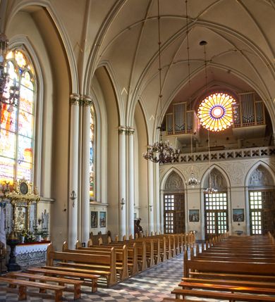 Zdjęcie nr 84: Kościół z cegły i kamienia. Na rzucie krzyża łacińskiego, jednonawowy z wciągniętymi do wnętrza przyporami. Prezbiterium krótkie, zamknięte pięcioma bokami ośmioboku. Korpus jednonawowy, czteroprzęsłowy, po bokach z płytkimi wnękami-kaplicami pomiędzy przyporami, poprzedzony od zach. przedsionkiem. Do pierwszego przęsła dostawione dwie symetryczne, trójboczne kaplice, nad nimi dwie czworoboczne wieże. Zakrystia przy prezbiterium na osi kościoła. Artykulacja ścian wnętrza za pomocą filarów opiętych półkolumnami z kapitelami z motywów liści. Między filarami rozpięte ostrołukowe arkady tworzące płytkie wnęki. Pierwsze przęsło wyróżnione przy pomocy masywnych filarów, ujętych niemal pełnoplastycznymi kolumnami. Okna ostrołukowe, dwudzielne z maswerkami, wsparte na gzymsach. Sklepienia krzyżowo-żebrowe na zaostrzonych gurtach. Kaplice artykułowane analogicznie do nawy kościoła, ze sklepieniami gwiaździstymi. Przedsionek otwiera się do kościoła trzema portalami ostrołukowymi opiętymi kolumnami. W polach archiwolt płaskorzeźby: Boże Narodzenie, Ukrzyżowanie, Wniebowstąpienie (K. Ceptowski).  W prezbiterium, na osi kościoła prostokątny otwór drzwiowy prowadzący do zakrystii. Chór muzyczny umieszczony nad kruchtą kościoła, na rzucie prostokąta, z kamienną balustradą maswerkową. Fasada kamienna, trójosiowa, zamknięta trójkątnie, flankowana lizenami przechodzącymi w ażurowe wieżyczki-latarnie, na rzucie kwadratu. Wieżyczki zwieńczone gzymsem i balustradą arkadową, hełmy ostrosłupowy zakończony iglicą. W dolnej części trzy filarowe arkady ostrołukowe, otwierające się do kruchty, sklepienie kruchty krzyżowo-żebrowe. Nad arkadami wejściowymi trzy tonda: litery IHS, Oko Opatrzności i splecione litery imienia Maria. Pośrodku na osi kościoła duża rozeta z maswerkiem, profilowana, otoczona pierścieniem wypełnionym stylizowanym ornamentem roślinnym. Ponad arkadami pełnoplastyczne figury czterech ewangelistów ustawionych na konsolach z rzeźbionymi atrybutami (F. Kuhn). Po bokach rozety prostokątne płyciny z traczami herbowymi Potockich i Branickich. U góry, na osi fasady figura Archanioła Michała. Elewacje na kamiennym cokole, z gzymsem kapnikowym, opięte prostokątnymi przyporami zwieńczonymi kamiennymi nakrywami. W górnej części kamienny fryz arkadkowy. Nad nim gzyms koronujący podtrzymujący ażurową, arkadową balustradę. Przy prezbiterium kaplice zamknięte trójbocznie, prezbiterium zamknięte pięciobocznie. Zakrystia na osi prezbiterium, na rzucie prostokąta, zwieńczona sygnaturką i ceglanym kominem. Po bokach prostokątne aneksy, południowy aneks - trzy okna ostrołukowe w kamiennej opasce, w środkowym przedstawienie Ukrzyżowanego Chrystusa. W północnym aneksie pojedyncze analogiczne okno. Okna ostrołukowe w profilowanych kamiennych opaskach, pomiędzy nimi a gzymsem koronującym mniejsze ostrołukowe w uskokowych arkadach. Nad kaplicami bocznymi dwie symetryczne wieże na rzucie kwadratu, w połowie wysokości kamienny gzyms z fryzem arkadkowym. Okna ostrołukowe w kamiennej opasce. Całość zwieńczona ślepym fryzem arkadkowym, wyżej gzyms dźwigający ażurową arkadkową balustradę. Hełmy ostrosłupowe, miedziane. Zakrystia na rzucie prostokąta, nakryta sklepieniem kolebkowym zaostrzonym i krzyżowym z lunetami , oddzielone gurtem. Portale od wschodu i zachodu prostokątne zamknięte łukiem ostrym. Okna ostrołukowe.